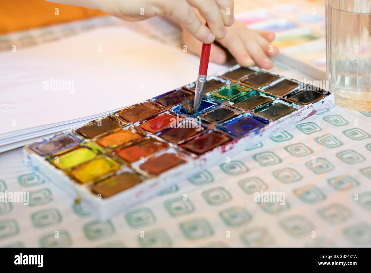 Nahaufnahme des Kindes, das sich mit Kunstwerken mit bunten gemischten Farben und Pinsel beschäftigt. Stockfoto