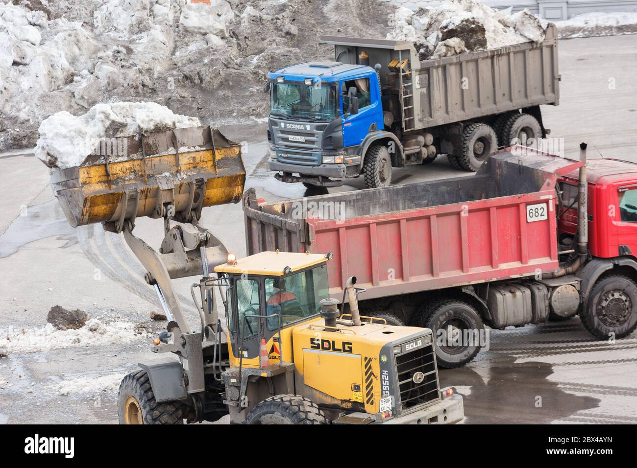 Novokusnezk. Russland. 09.04.2020. Das Gebiet mit schweren Geräten vom Schnee reinigen und in LKWs verladen. Redaktionell. Stockfoto