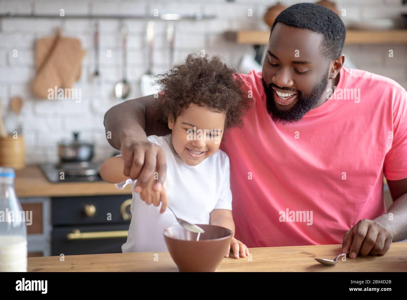 afroamerikanischer bärtiger Mann, der Milch in seinem Töchterteller rührt Stockfoto