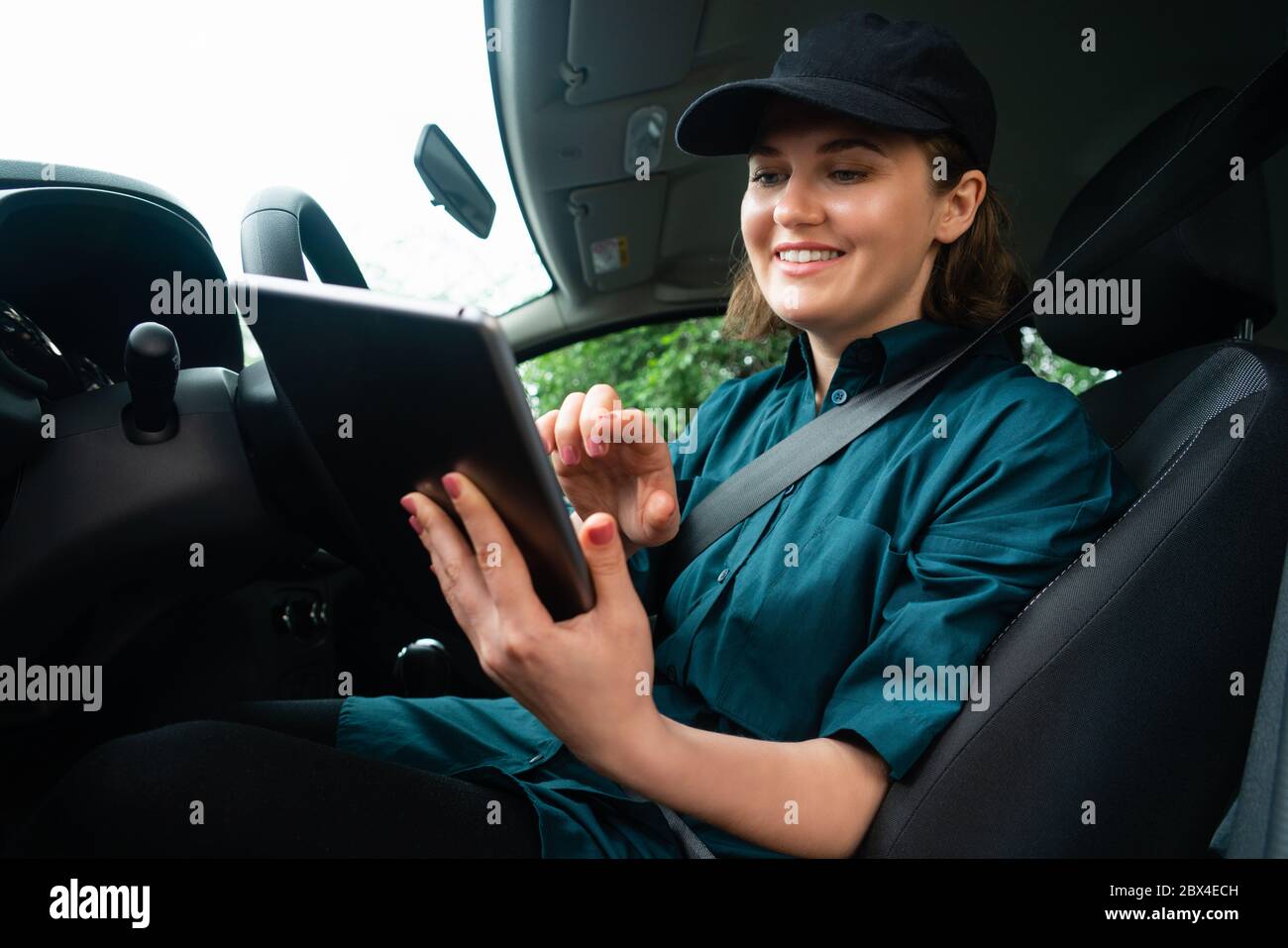 Kurierfrau sitzt in einem Auto und schaut auf ein digitales Tablet Stockfoto