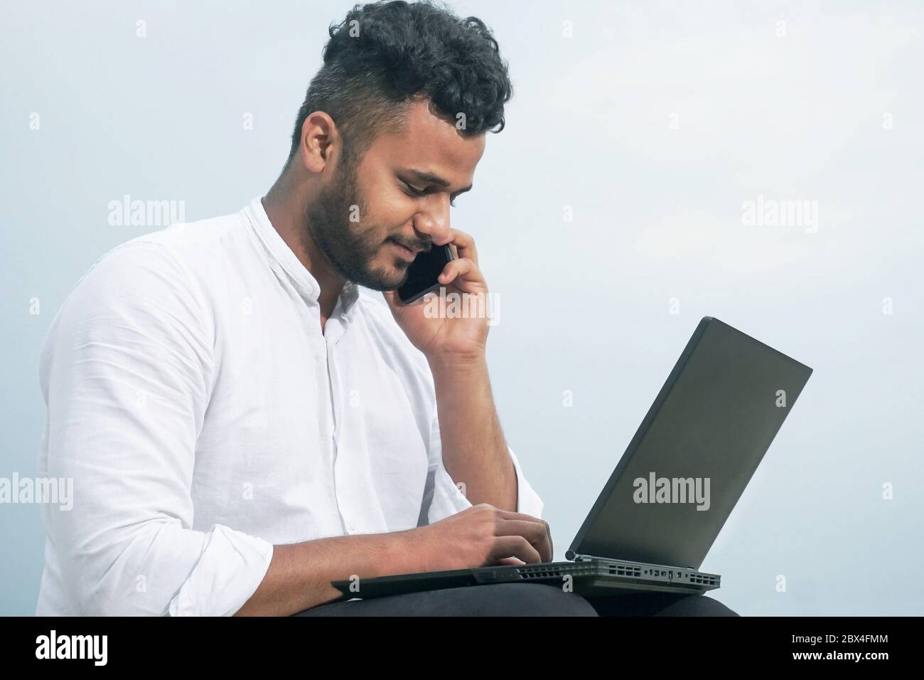 Junger Mann, der Laptop und Smartphone zusammen benutzt Stockfoto