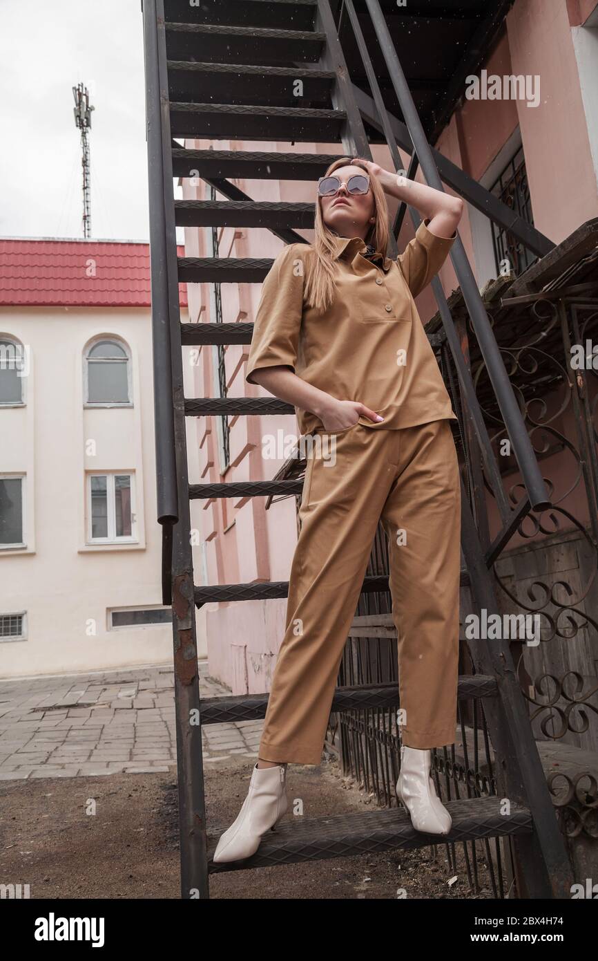 Ein schönes russisches Model im Teenageralter posiert auf Treppen. Natürliche Haut ohne Retuschuranatuschal. Städtischer dunkler Hintergrund. Tageslicht. Im Freien Stockfoto