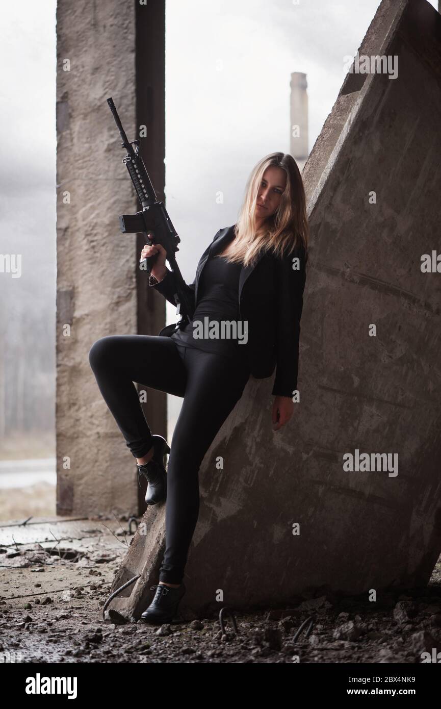 Frau mit Maschinengewehr in einem verlassenen Gebäude Stockfoto