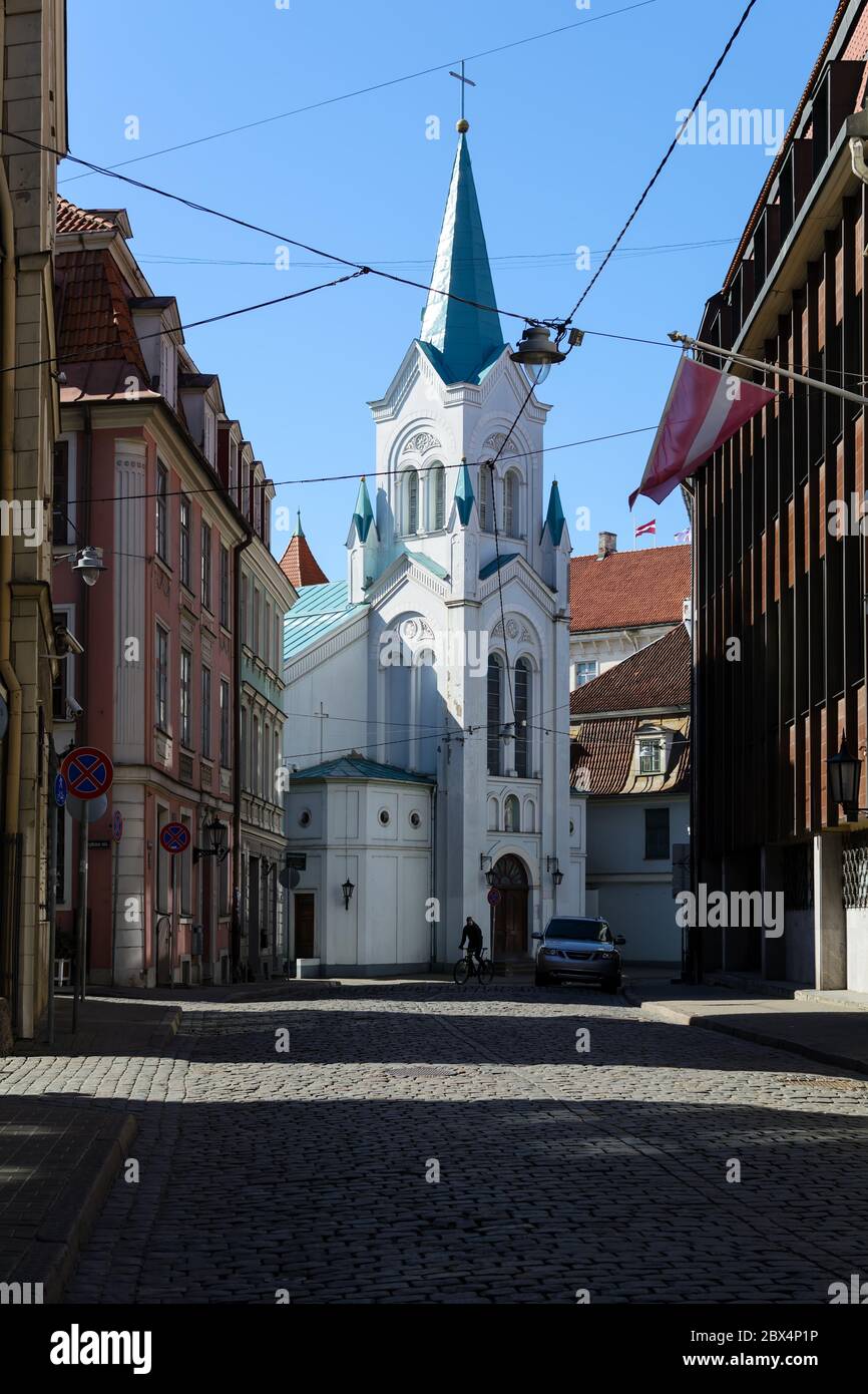 Einsamer Fahrradfahrer in der leeren Straße der Altstadt von Riga Stockfoto