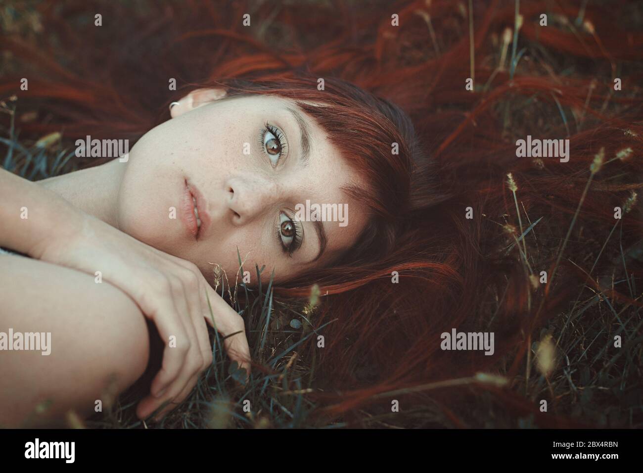 Rote Haare Frau posiert auf Gras. Einfaches Herbstporträt Stockfoto