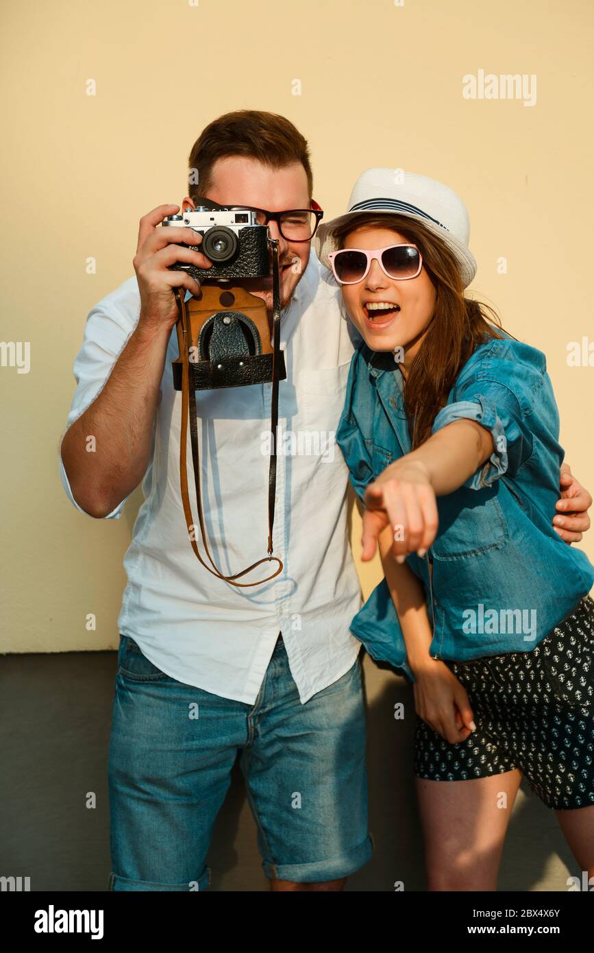Porträt eines schönen Hipster-Paares. Positiver Kerl in einem Hemd und Jeans. Mädchen in Hut und Sonnenbrille lächelt vor einem gelben Hintergrund Stockfoto