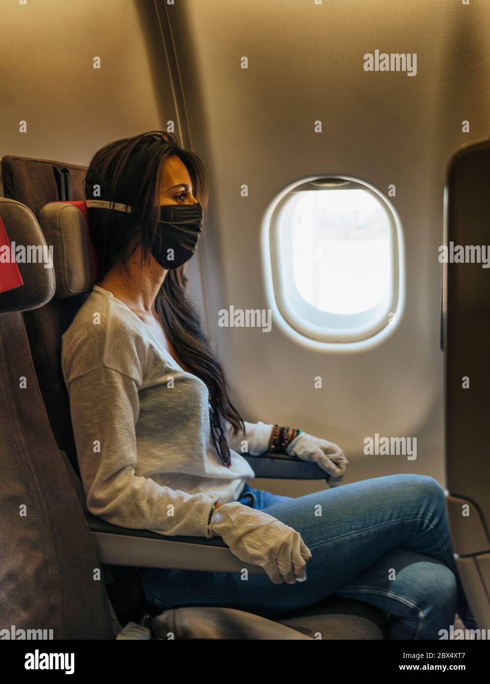 Frau in einem Flugzeug mit Gesichtsmaske Schutz, Coronavirus COVID19 Virus Stockfoto