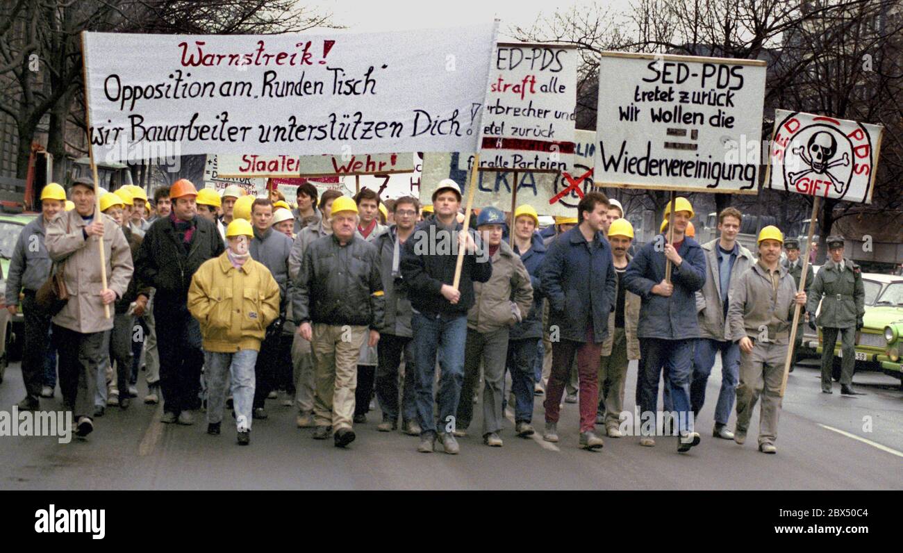 Berlin / DDR / 1990 Bauarbeiter der Friedrichstraße marschieren in die Volkskammer. Hier: Unter den Linden. Der Runde Tisch hat Schwierigkeiten mit der Regierung Modrow (SED/PDS). Sie wollen Druck ausüben. Forderung: Wir wollen die Wiedervereinigung. -Keine Stasi, keine SED, sonst verabschiede ich mich von der DDR -der protestmarsch unter den Linden Forderungen: -Wir wollen Wiedervereinigung. -die SDP/SPD war stark in der Firma Ingenieur-hoch-Bau. Einer der Organisatoren war Knut Herbst, Abgeordneter des landtags in Berlin der Mittelträger (schwarze Jacke) ist Ralf Hillenberg, SPD-Politiker / Runde Stockfoto