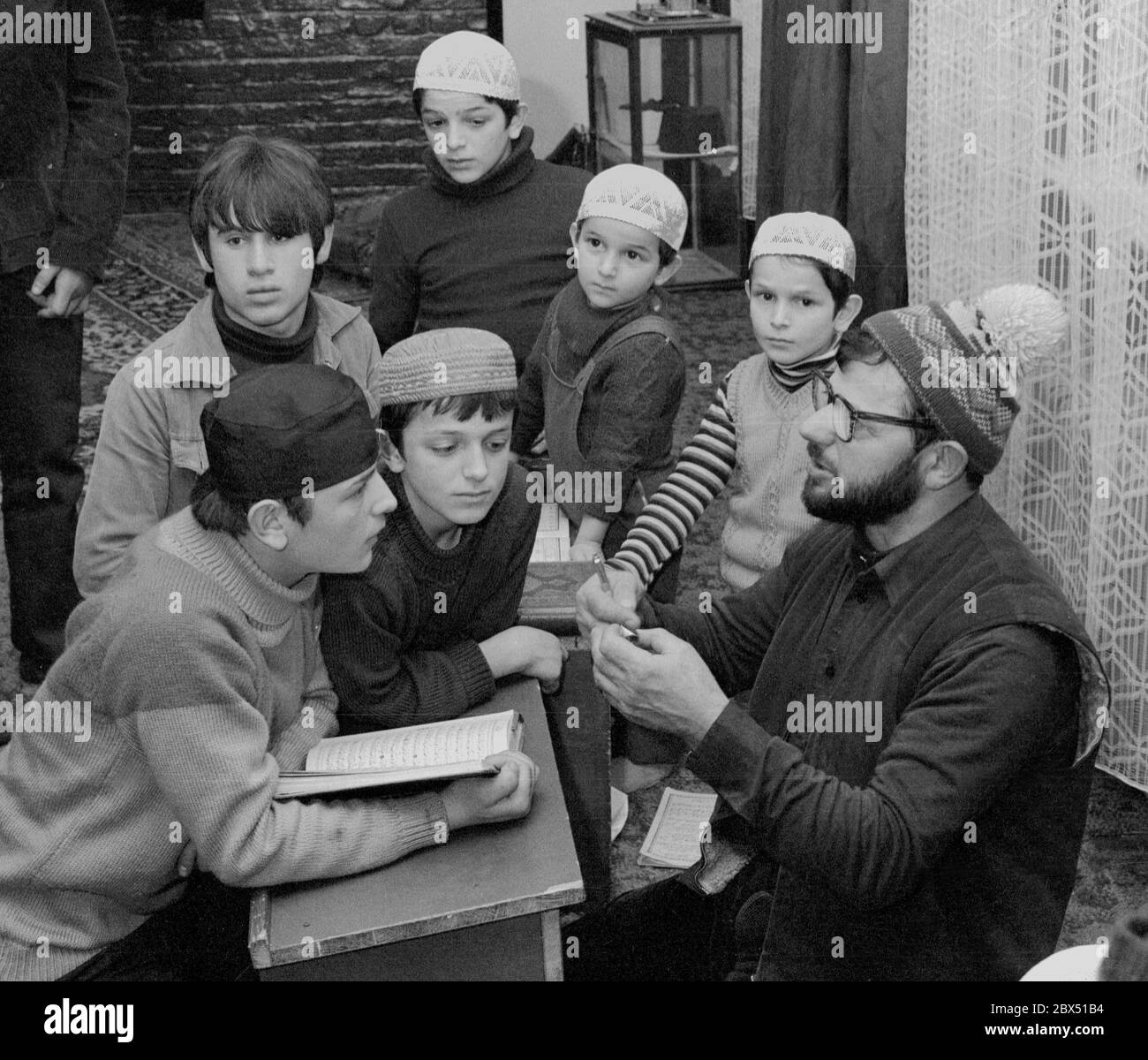 Berlin-Kreuzberg / Ausländer / Türken / 25.2.1980 KORANKURS in der Fatih-Moschee, organisiert von türkischen Arbeitern. Die Moschee gehört der Islamischen Föderation an, die nicht auf Regierungsebene ist. Darin sind auch sehr fundamentalistische islamische Richtungen. Die Fatih Moschee ist moderat. Die Hodja liest eine Sura, die Kinder wiederholen sie, bis sie fertig ist. Du kannst auch einige arabische Schriftzeichen lernen. Der Korankurs befindet sich in einer verlassenen Fabrikhalle, die mit Teppichen bedeckt ist. // Islam / Schule / Zoll / [automatisierte Übersetzung] Stockfoto