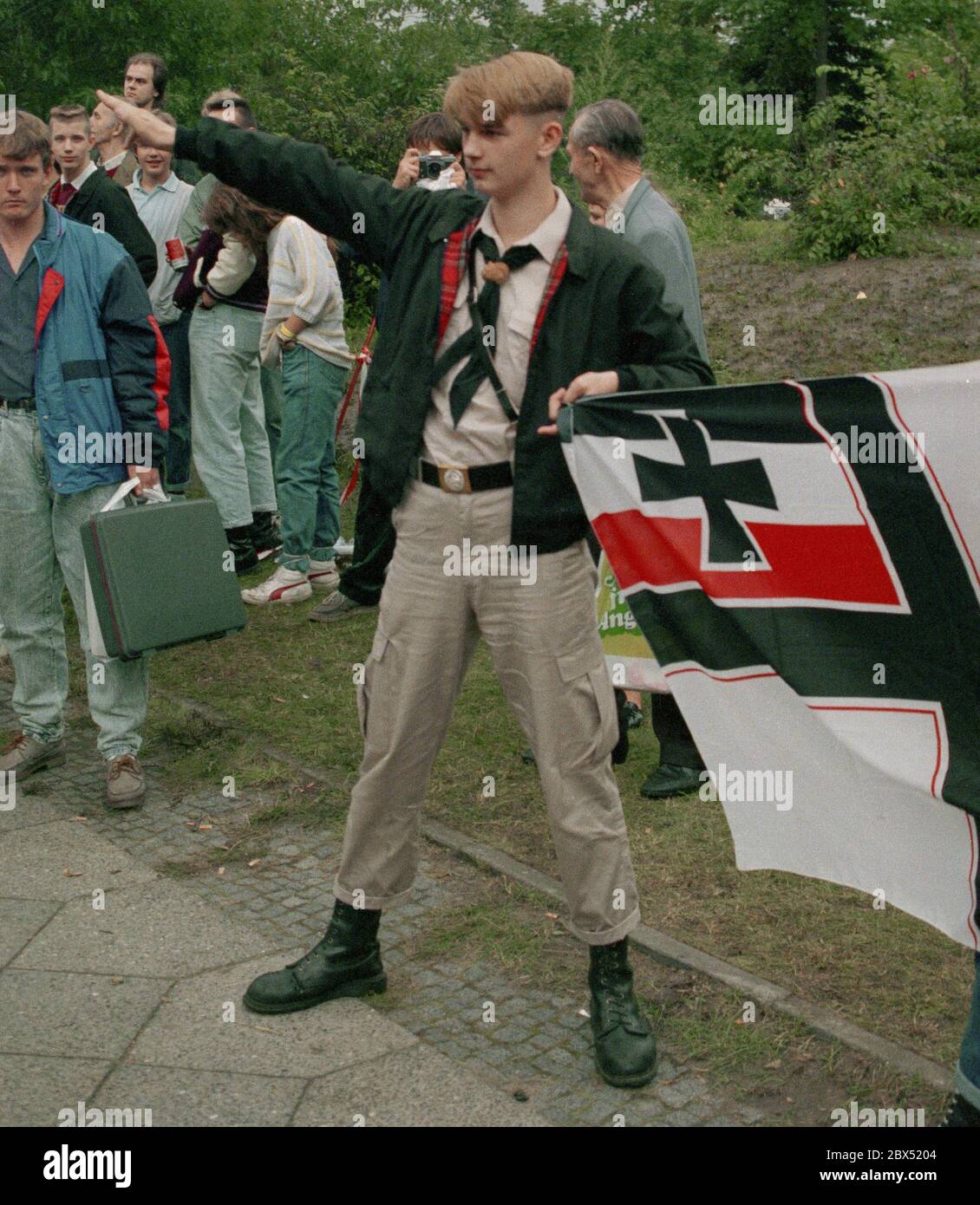 Berlin-Spandau / Nazis / Rechtsgruppen 20.8.1987 vor dem Kriegsverbrechergefängnis in Spandau ist Rudolf Hess gerade gestorben. Die rechten Gruppen versammeln sich in Trauer. Der junge Rechtsradikale Michael Wendt (rechts) mit der Reichskriegsfahne und dem Kühnen-Gruß, einer Variante des Hitlergrüßens, der verboten wurde. Ein Polizist fragt, worum es hier geht. Blumen vor Hess. // Nazi / Faschismus / *** Ortsunterschrift *** das Gefängnis für Kriegsverbrecher in Berlin-Spandau. Der letzte Gefangene, Rudolf Hess, starb nach 46 Jahren im im Hintergrund gezeigten Gefängnis. Rechter Flügel Stockfoto