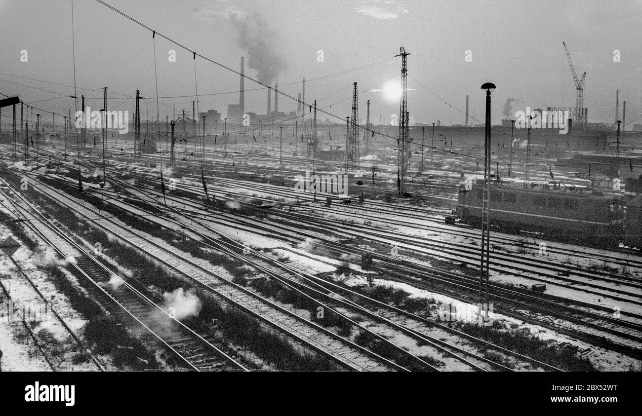 Sachsen-Anhalt / DDR Land / Winter / Dezember 1989 Winterabend in Bitterfeld, Sonnenuntergang hinter dem Braunkohlekombinat, Bahngelände vor // Stimmung / Wirtschaft / Vertrauen / Industrie / Landschaft 1894 die Firma Chemische Fabrik Griesheim (Frankfurt am Main) Baut in Bitterfeld eine Fabrik zur Herstellung von chloriertem Kalk durch Elektrolyse. 1900 wurde das Verfahren auch zur Gewinnung von Magnesium und Aluminium eingesetzt, 1923 zog Griesheim komplett nach Bitterfeld. In der Nähe der Braunkohlebergwerke siedelten sich weitere Firmen an: Agfa baute eine Farb- und eine Folienfabrik. 1990 ging das Ende. Das VEB Chemiekombinat Stockfoto