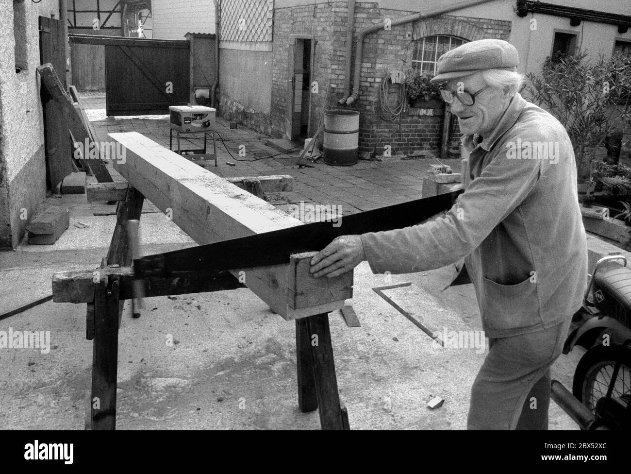 Sachsen-Anhalt / Harz / DDR-Land / 08/1990 Ostharz: Fachwerkstadt Osterwieck. Ein 76-jähriger Rentner muss wieder arbeiten. Zimmerleute werden benötigt, um die alten Häuser zu reparieren. In der DDR gab es viele Betonhandwerker, aber nur wenige Handwerker, die mit schiefen Balken auskommen konnten. // Alt / Handwerk / Arbeit / Menschen [automatisierte Übersetzung] Stockfoto