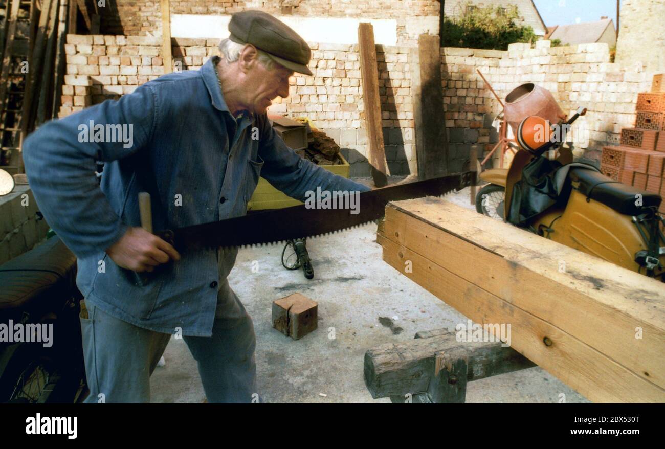 Sachsen-Anhalt / Harz / DDR-Land / 08/1990 Ostharz: Fachwerkstadt Osterwieck. Ein 76-jähriger Rentner muss wieder arbeiten. Zimmerleute werden benötigt, um die alten Häuser zu reparieren. In der DDR gab es viele Betonhandwerker, aber nur wenige Handwerker, die mit schiefen Balken auskommen konnten. // Alt / Handwerk / Arbeit / Menschen [automatisierte Übersetzung] Stockfoto