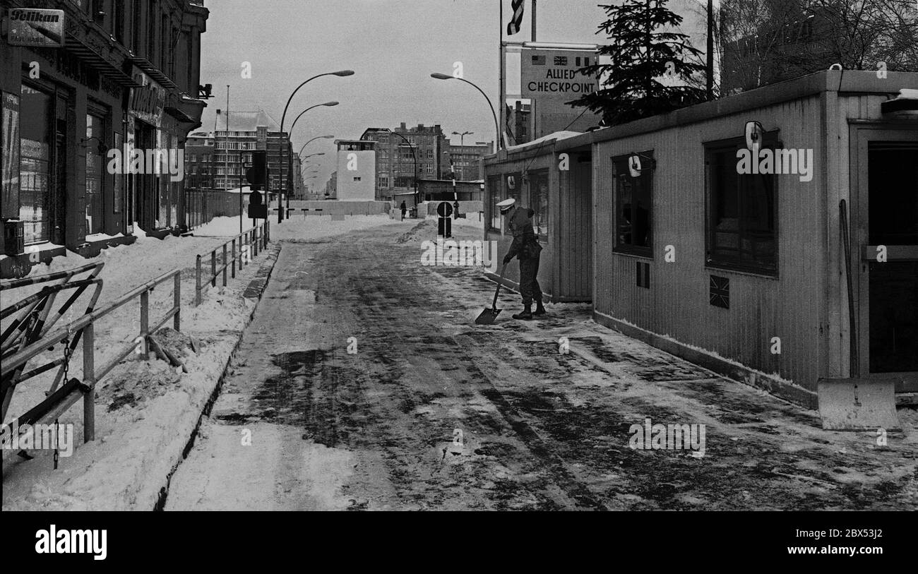 Berlin Bezirke / Alliierte / Besetzung / 1976 Kreuzberg, Weihnachten 1976, Bürgermeister Rudi Pietschker, SPD, bringt Weihnachtsgeschenke an Checkpoint Charly die Offiziere der Westalliierten: Frankreich, England, USA, sind dabei, sich an der Friedrichstraße zur Pflicht zu melden. Ein amerikanischer Soldat schiebt den Schnee weg. // Besatzungsmacht / Geschichte / [automatisierte Übersetzung] Stockfoto