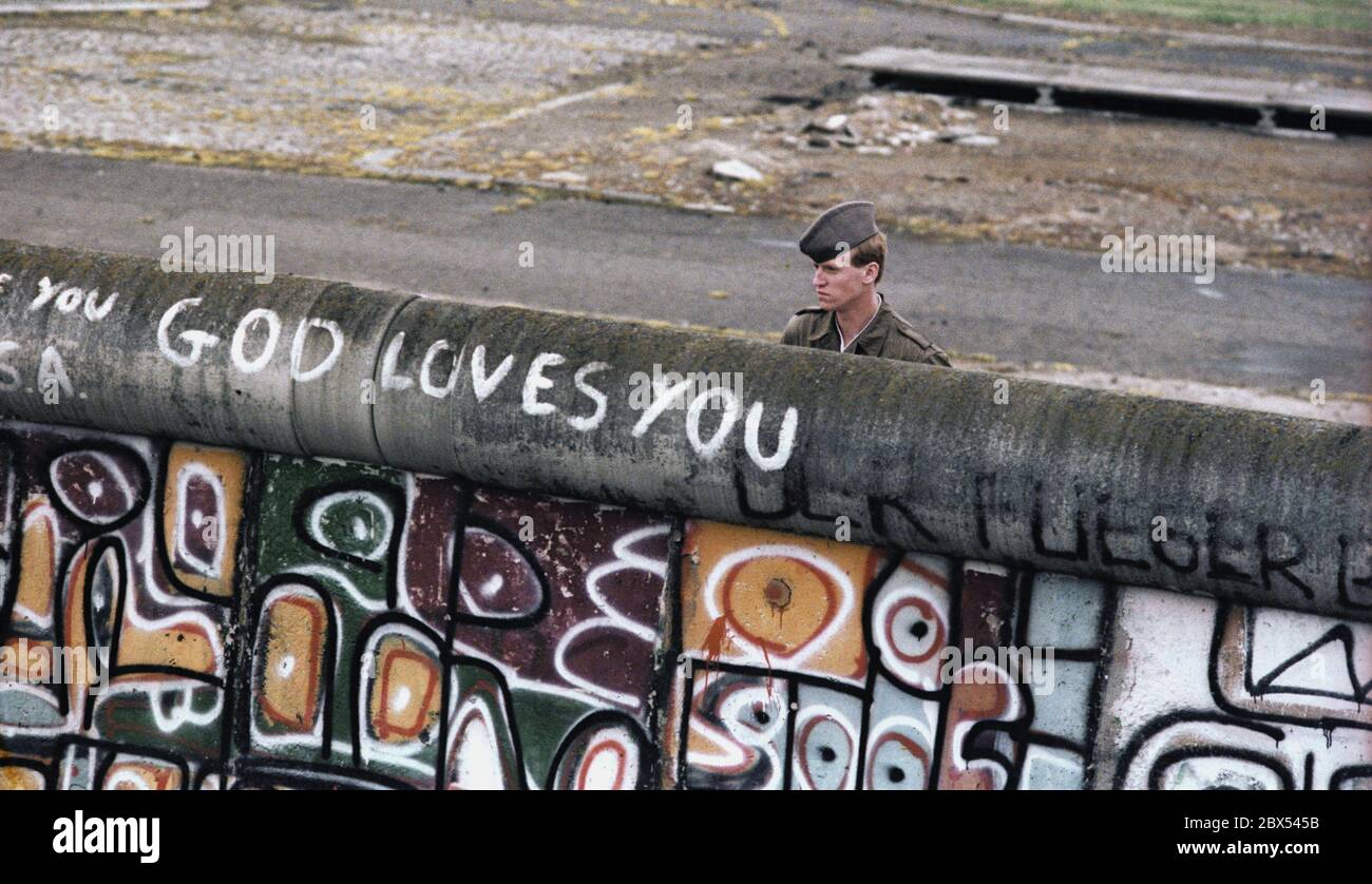 Berlin-City / Mitte / DDR / 6 / 1988 Potsdamer Platz: DDR-Grenzposten blicken nach West-Berlin. Junge Leute haben dort ein Stück Niemandsland besetzt. Sie liegt im Westen, gehört aber zum Osten. Die West-Berliner Polizei ist dabei, evakuiert zu werden. Der DDR-Grenzschutz weiß nicht, was auf der Westseite der Mauer steht: -Gott liebt dich- // DDR-Mauer / Geschichte / Kommunismus / DDR-Staat [automatische Übersetzung] Stockfoto