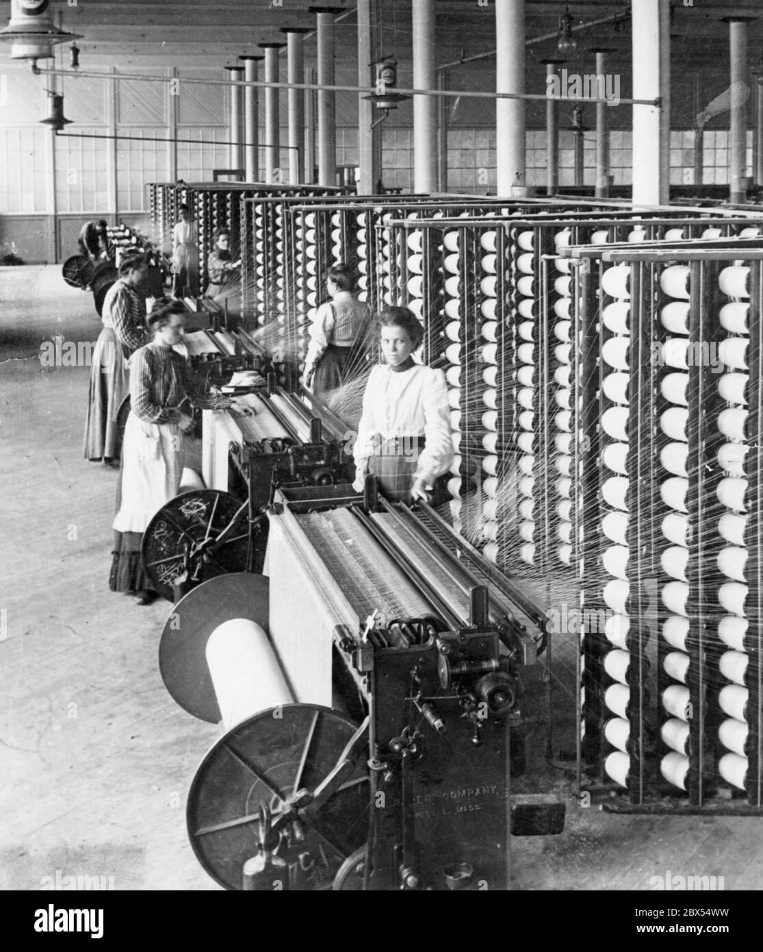 Frauen arbeiten an mechanischen Webstühlen in einer Baumwollspinnerei. Stockfoto