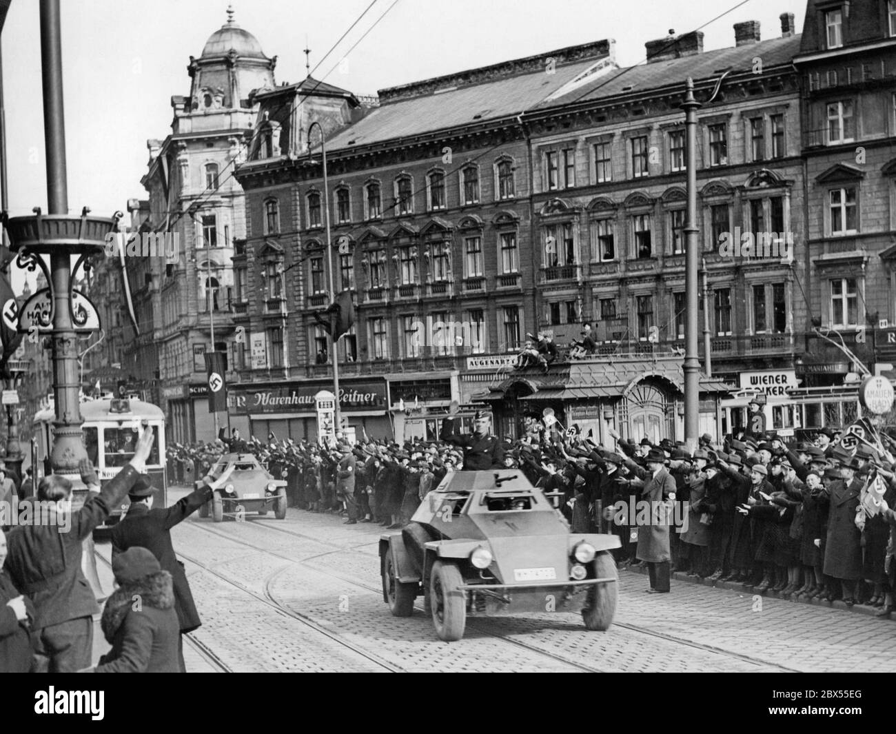 Deutscher Panzerspaehwagen Sdkfz. 221 (leichtes Panzeraufklärungsfahrzeug) durch die Mariahilfer Straße in Wien fahren. Auf der Straße befindet sich das Kaufhaus Leitner, ein Augenarzt und die Wiener Molkerei. Stockfoto