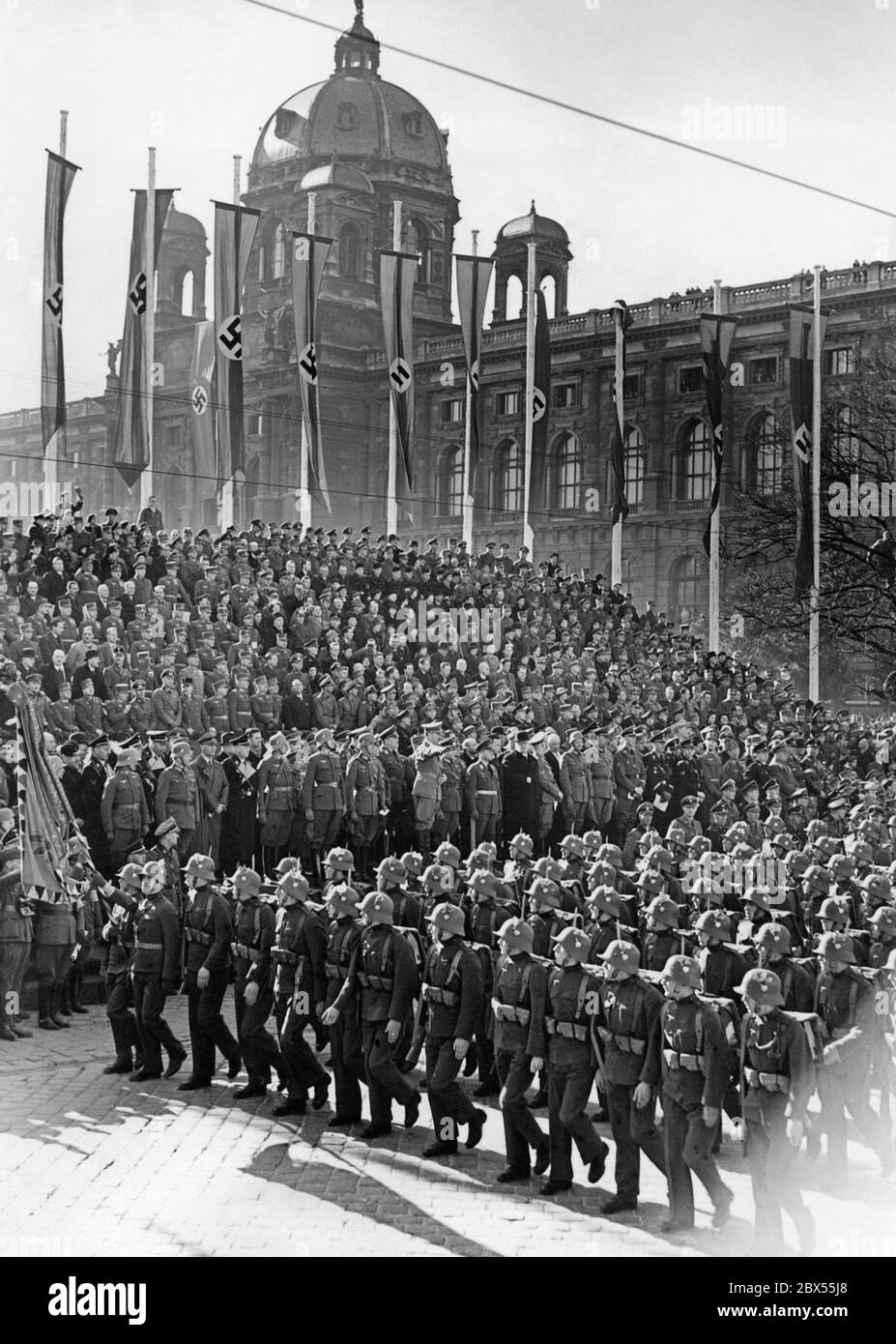 Marsch der Soldaten vor Adolf Hitler während der Militärparade auf dem Heldenplatz in Wien. Die Parade findet im Rahmen der Feierlichkeiten zur Annexion Österreichs an das Deutsche Reich statt. Die österreichischen Soldaten tragen bereits das deutsche Staatswappen auf ihren Stahlhelmen und Uniformen. Stockfoto