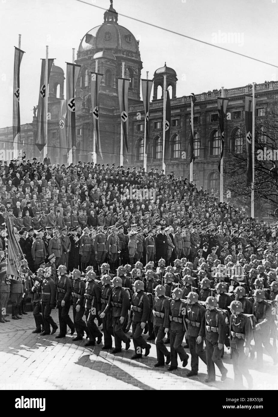 Marsch der Soldaten vor Adolf Hitler während der Militärparade auf dem Heldenplatz in Wien. Die Parade findet im Rahmen der Feierlichkeiten zur Annexion Österreichs an das Deutsche Reich statt. Die österreichischen Soldaten tragen bereits das deutsche Staatswappen auf ihren Stahlhelmen und Uniformen. Stockfoto