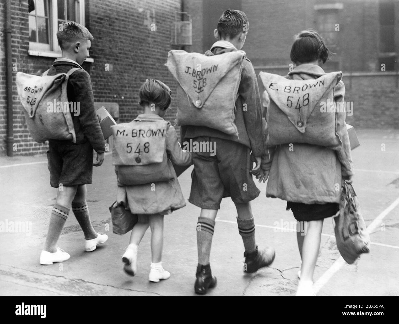 Die vier Kinder der Familie Brown sind auf dem Weg zu ihrer Schule in Clerkenwell Green, die in den Ferien speziell für Evakuierungsübungen geöffnet wurde. Ihre Namen und Nummern sind auf den Rucksäcken der Kinder geschrieben. Stockfoto