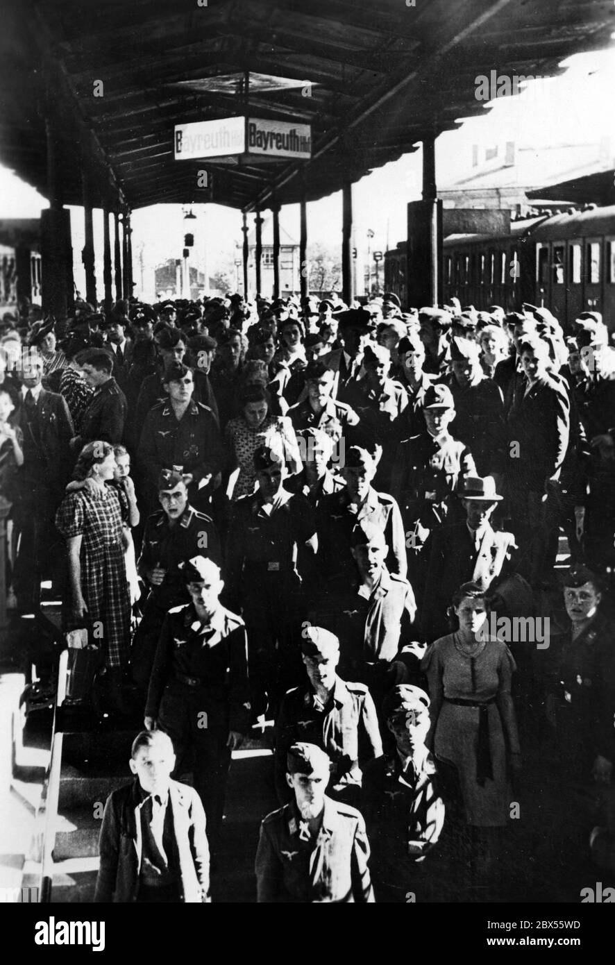 Adolf Hitlers geladene Gäste, ausnahmslos Wehrmachtsangehörige sowie Rüstungsarbeiter, kommen auf dem Weg zum Fest am Bayreuther Bahnhof an. Stockfoto