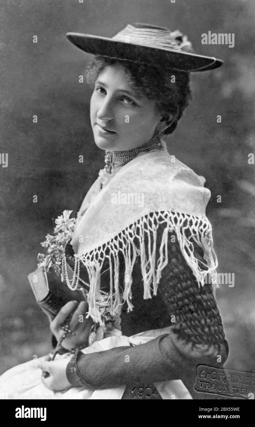 Ein Mädchen aus Traunstein in einem traditionellen Dirndl mit Kreuz und Bibel in den Händen. Stockfoto