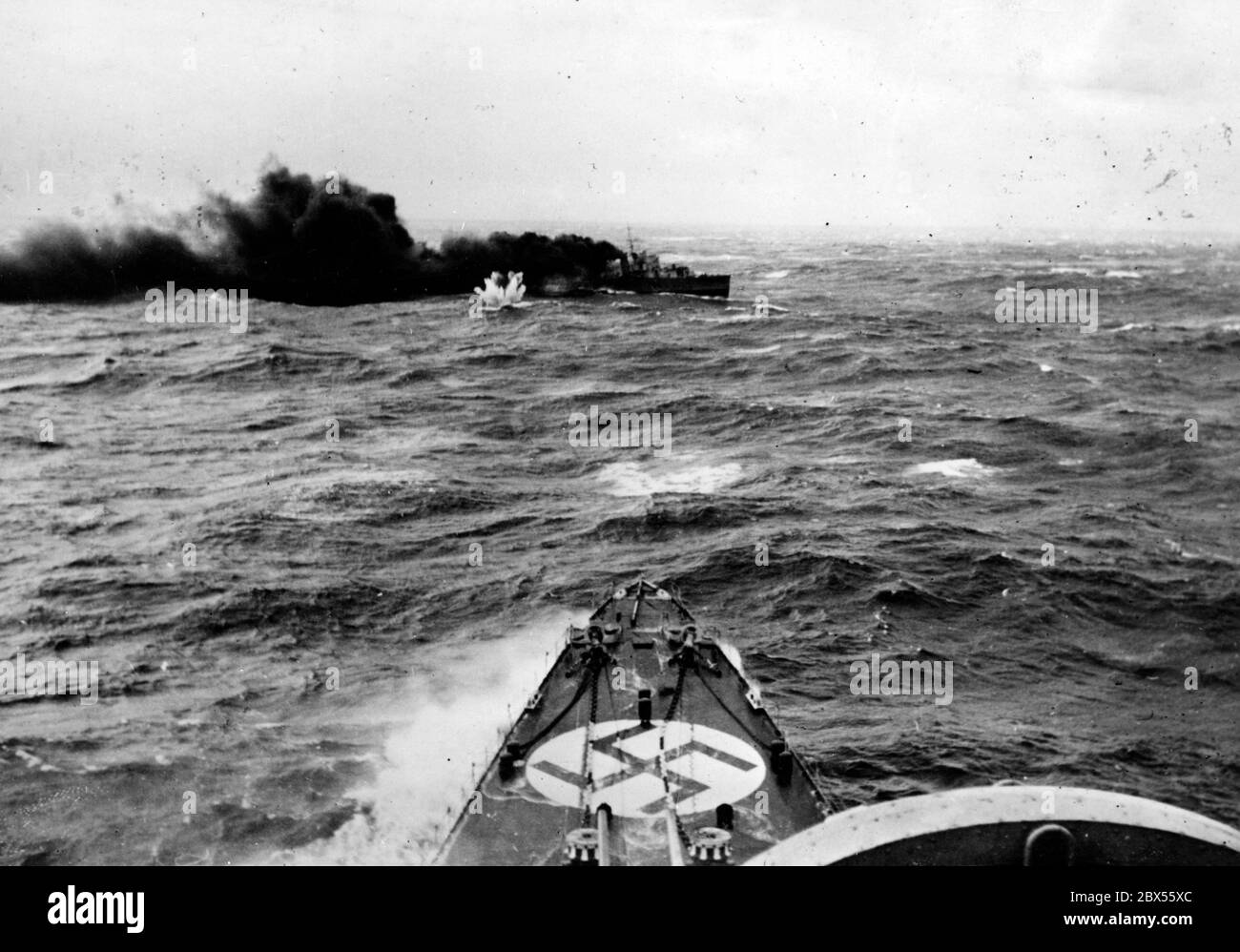 Ein englischer Zerstörer wird bei einer Kreuzfahrt nach Norwegen angegriffen. Im Vordergrund steht der Bug eines deutschen Kriegsschiffes. Dies ist wahrscheinlich der Untergang des britischen Zerstörers HMS Glowworm durch den deutschen schweren Kreuzer Admiral Hipper am 08.04.1940. Stockfoto