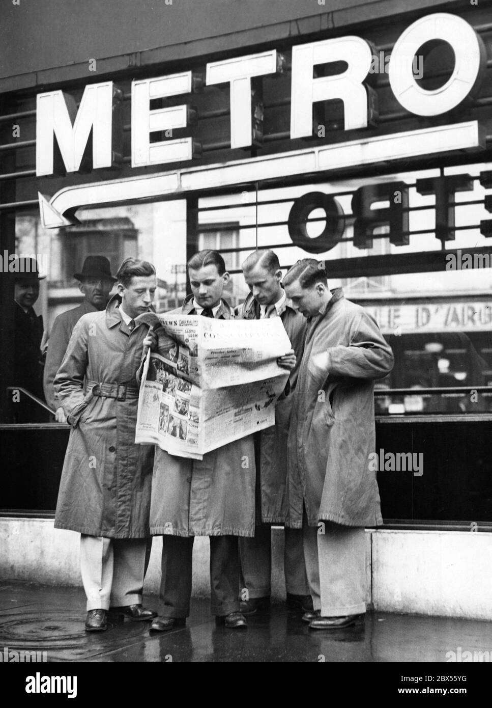 Eine Gruppe junger Männer las zusammen die aktuellen Ereignisse in der britischen Zeitung 'Daily Express'. Die Überschrift "Wehrpflicht" kündigt den Truppeneinruf an. Stockfoto