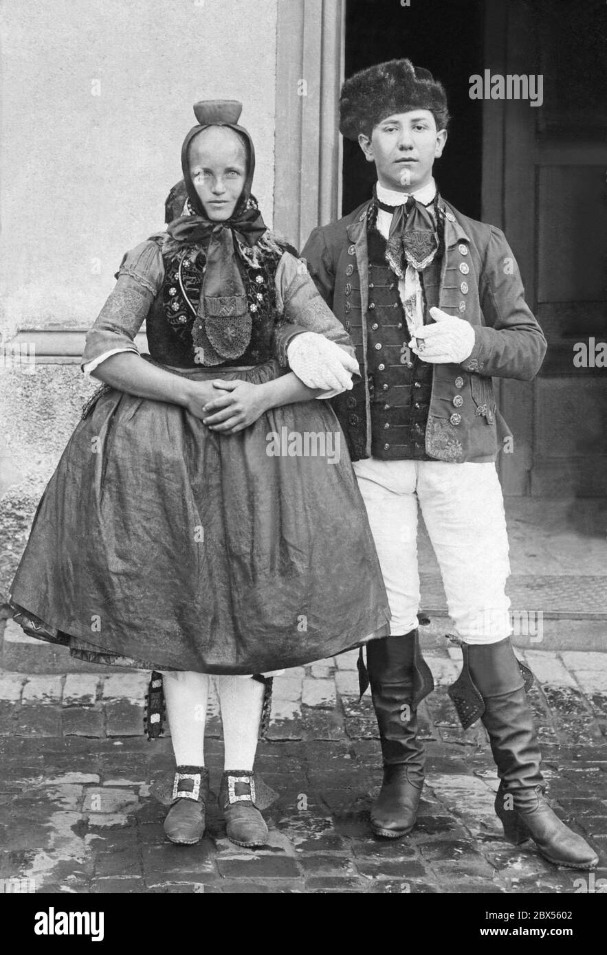 Ein Paar aus Schrecksbach in Nordhessen in typischer Tracht aus der Schwalm Region. Die Frau trägt Schnallen, breite Röcke und Betzel (Haube) auf dem Kopf. Der Mann trägt Lederstiefel, weiße Hosen und weiße Handschuhe. Stockfoto