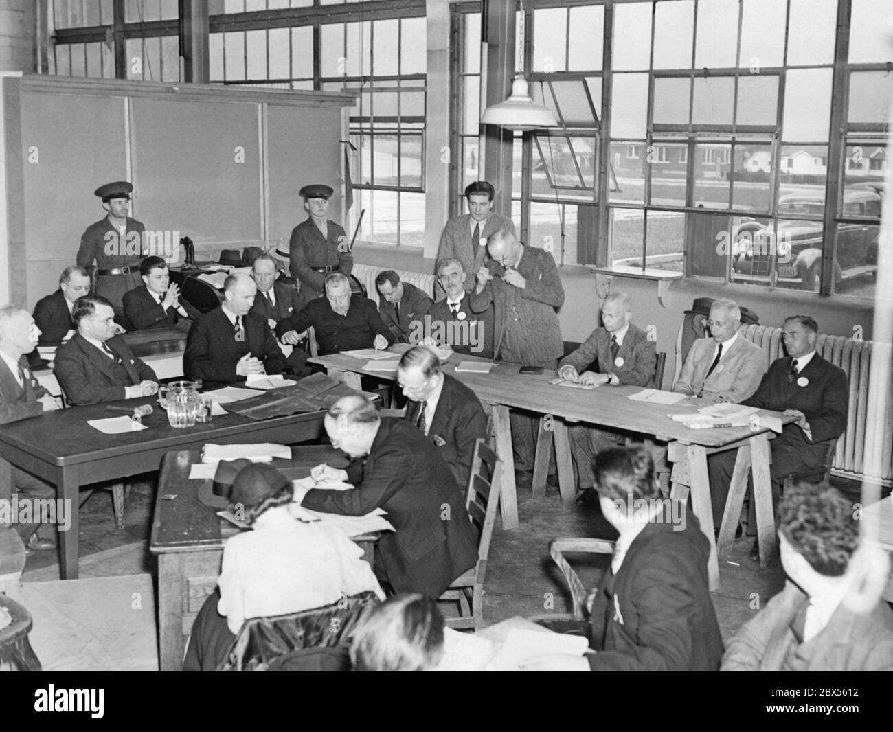 Deutsche und amerikanische Ermittler bei Verhören, um den Verlauf der Ereignisse und Ursachen der Hindenburg-Katastrophe zu ermitteln. Die deutschen Ermittler sitzen rechts. Stockfoto