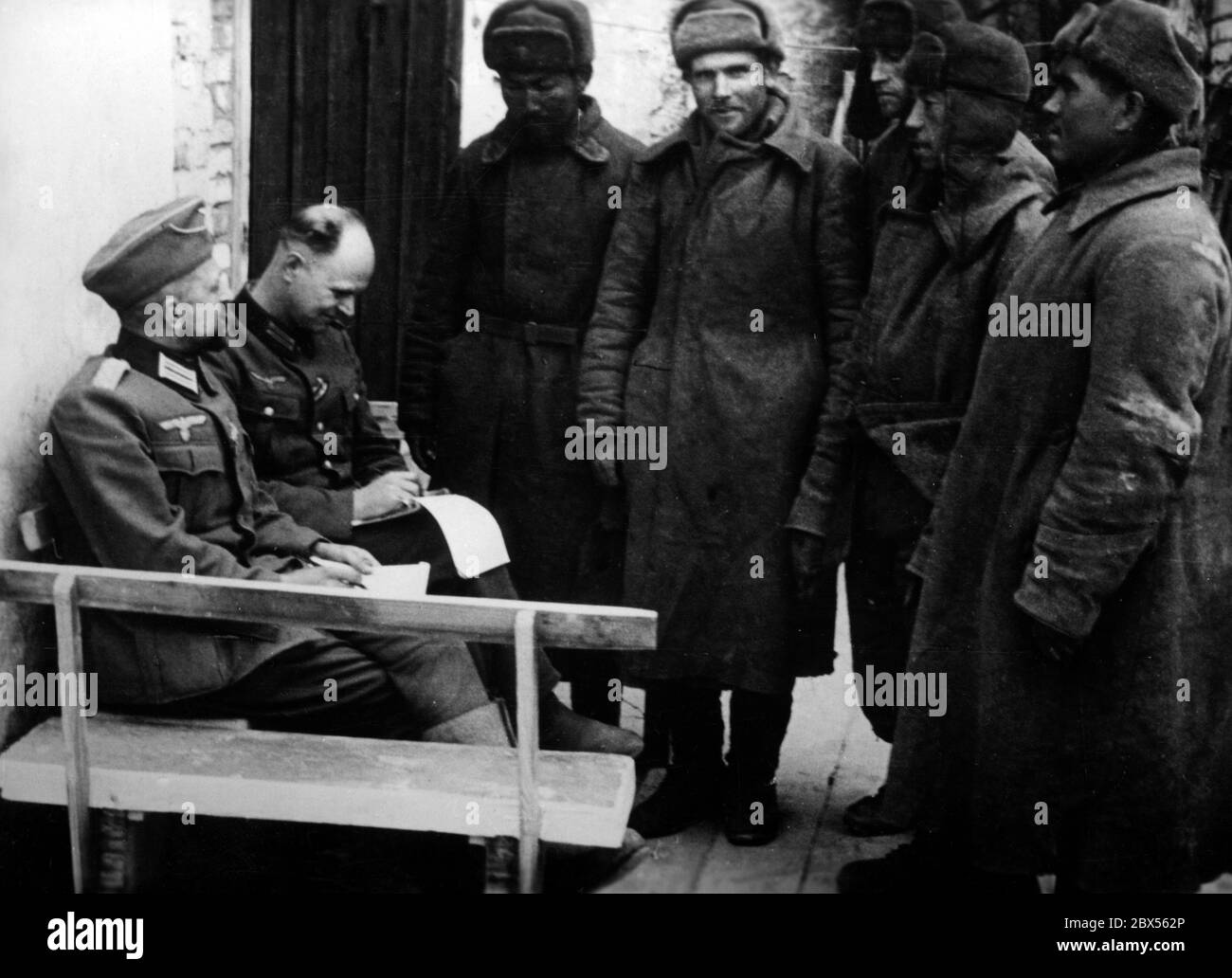 Zwei deutsche Offiziere verhören fünf sowjetische Gefangene in Cholm. Während der Einkreisungsschlacht von Kholm verteidigte die Kampfgruppe Scherer die Stadt erfolgreich für 105 Tage. (Ein Foto der Propaganda Company (PK) des Kriegsberichterstatters Richard Muck, der Anfang März in die Tasche flog). Stockfoto