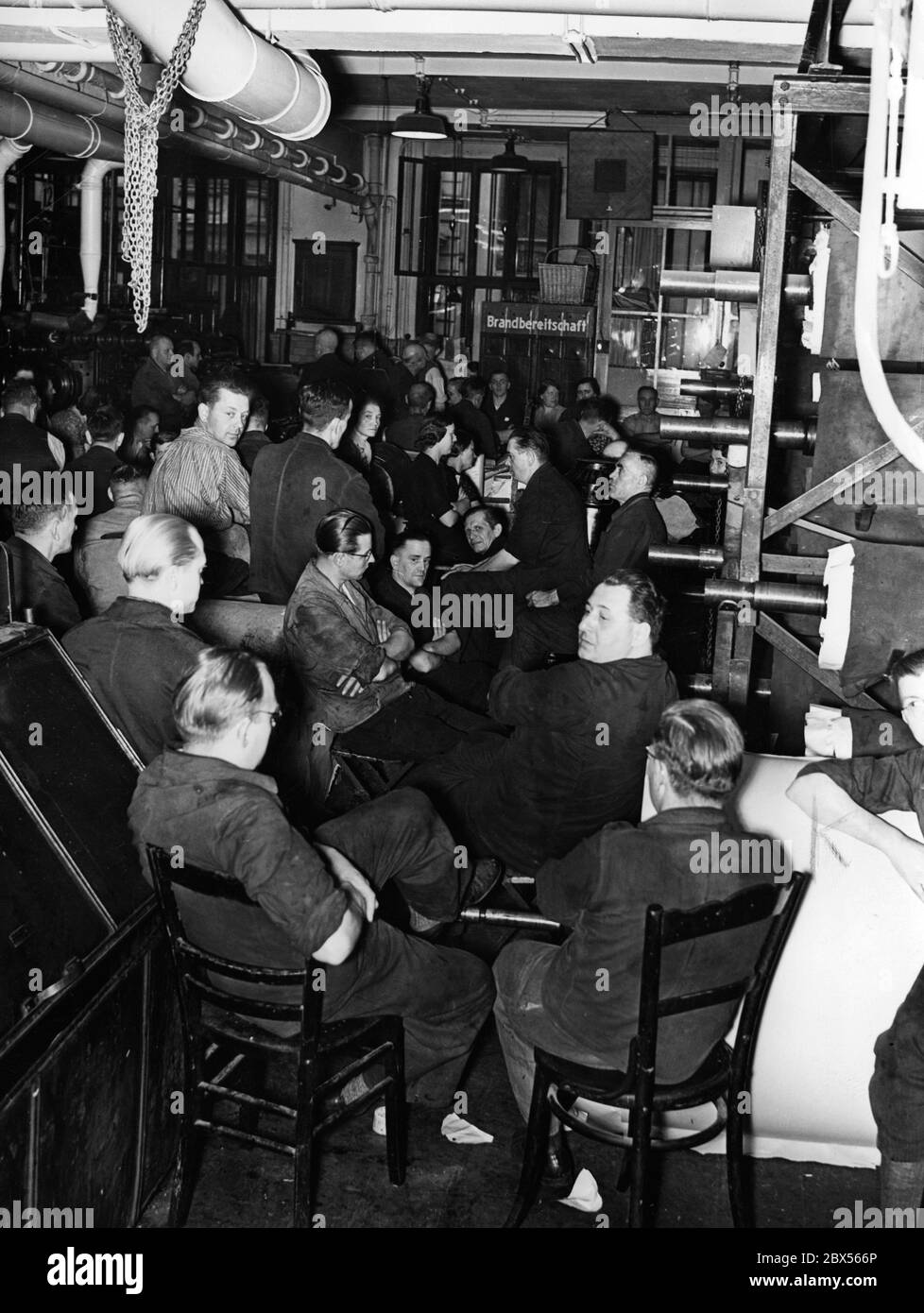 Mitarbeiter der Tiefdruckabteilung versammeln sich in der Druckmaschine, um eine Rede des Führers zu hören. Stockfoto