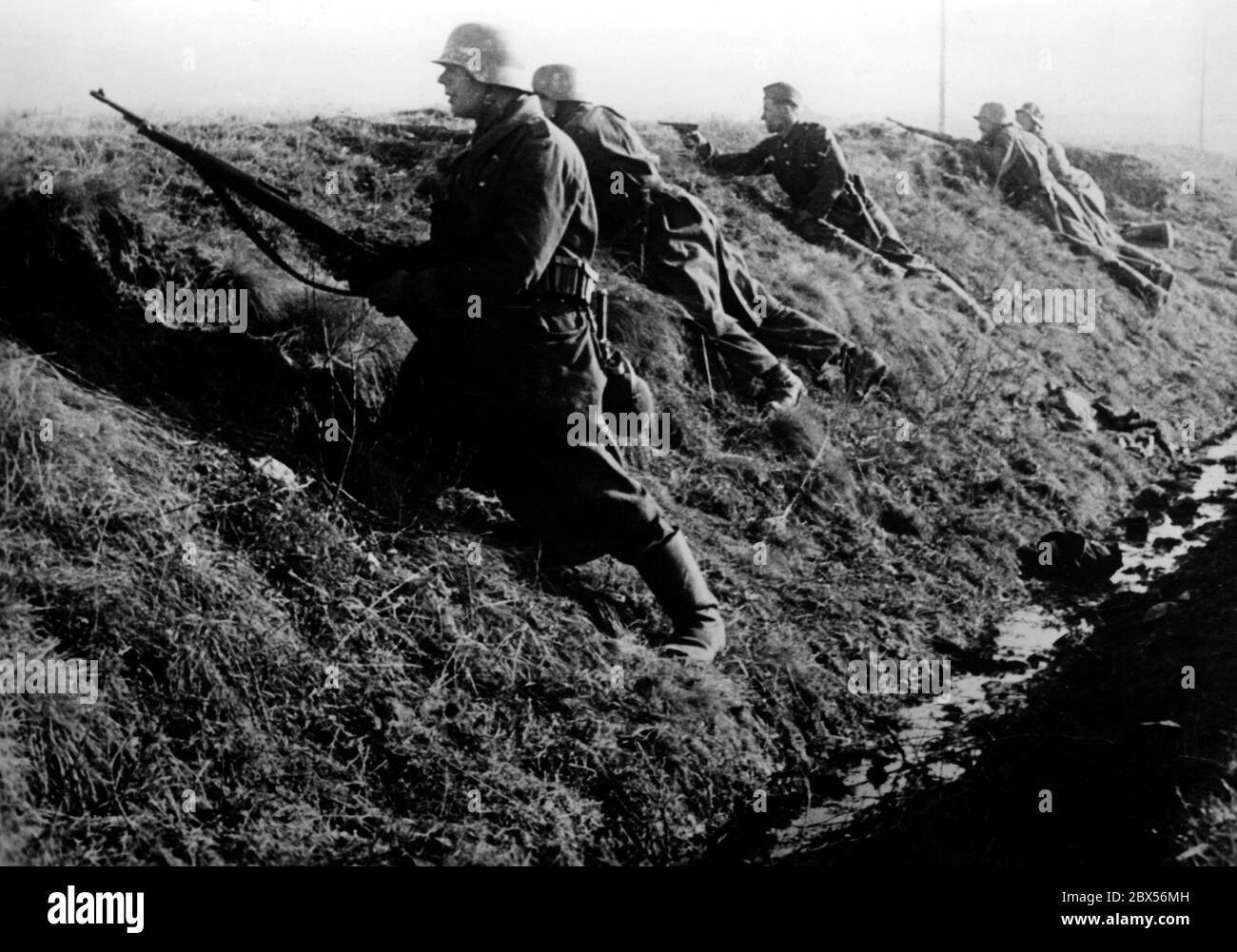Nach dem Abschuss von drei sowjetischen Panzern kommt ein Angriffskommando vor, um die Situation zu untersuchen. Hier sind sie noch unter Deckung. Während der Einkreisungsschlacht von Kholm verteidigte die Kampfgruppe Scherer die Stadt erfolgreich für 105 Tage. (Ein Foto der Propaganda Company (PK) des Kriegsberichterstatters Richard Muck, der Anfang März in die Tasche flog). Stockfoto