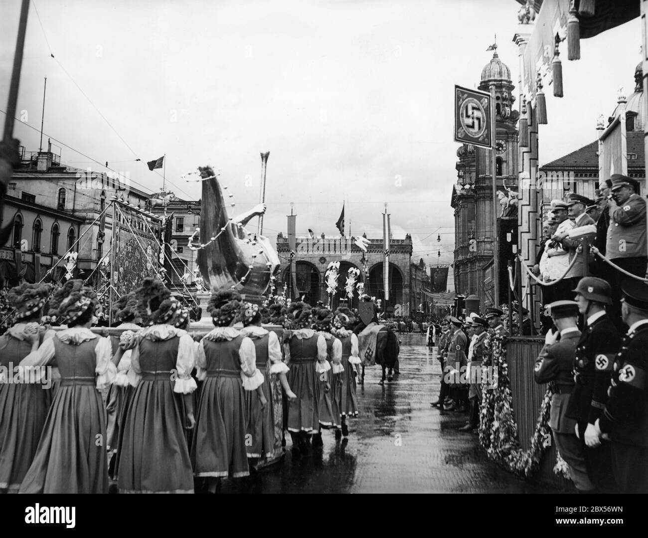 Am Tag der deutschen Kunst findet in München eine Parade statt. Hier marschiert die Sudetenlandgruppe in Tracht mit einer Skulptur und einer Karte am Odeonsplatz vor der Feldherrnhalle und der Theatinerkirche vorbei an der VIP-Tribüne. Auf diesem Stand von links nach rechts: Dino Alfieri, Adolf Hitler, Heinrich Hoffmann, der fotografiert. Im Hintergrund Joseph Goebbels und Adolf Wagner. Stockfoto