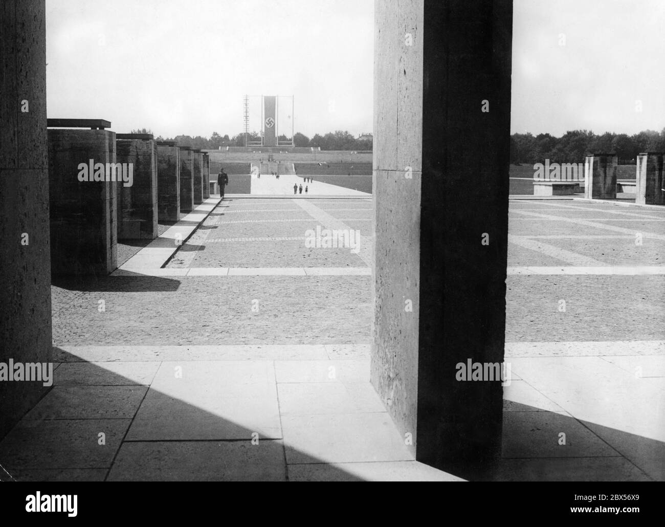 Blick von der Ehrenhalle auf das Rurum der Luitpold Arena auf dem Nürnberger Festgelände. Über der Tribüne hängt eine Hakenkreuzfahne. Ein breiter Granitweg führt direkt von der Ehrenhalle zur Tribüne. Stockfoto