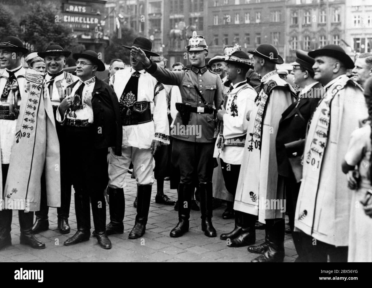 Eine Gruppe von Sängern aus Siebenbürgen in Tracht, die zum Saengerbundesfest in Breslau sind, wird von einem Polizisten in die Wege geleitet. Im Hintergrund der Ratsweinkeller. Stockfoto