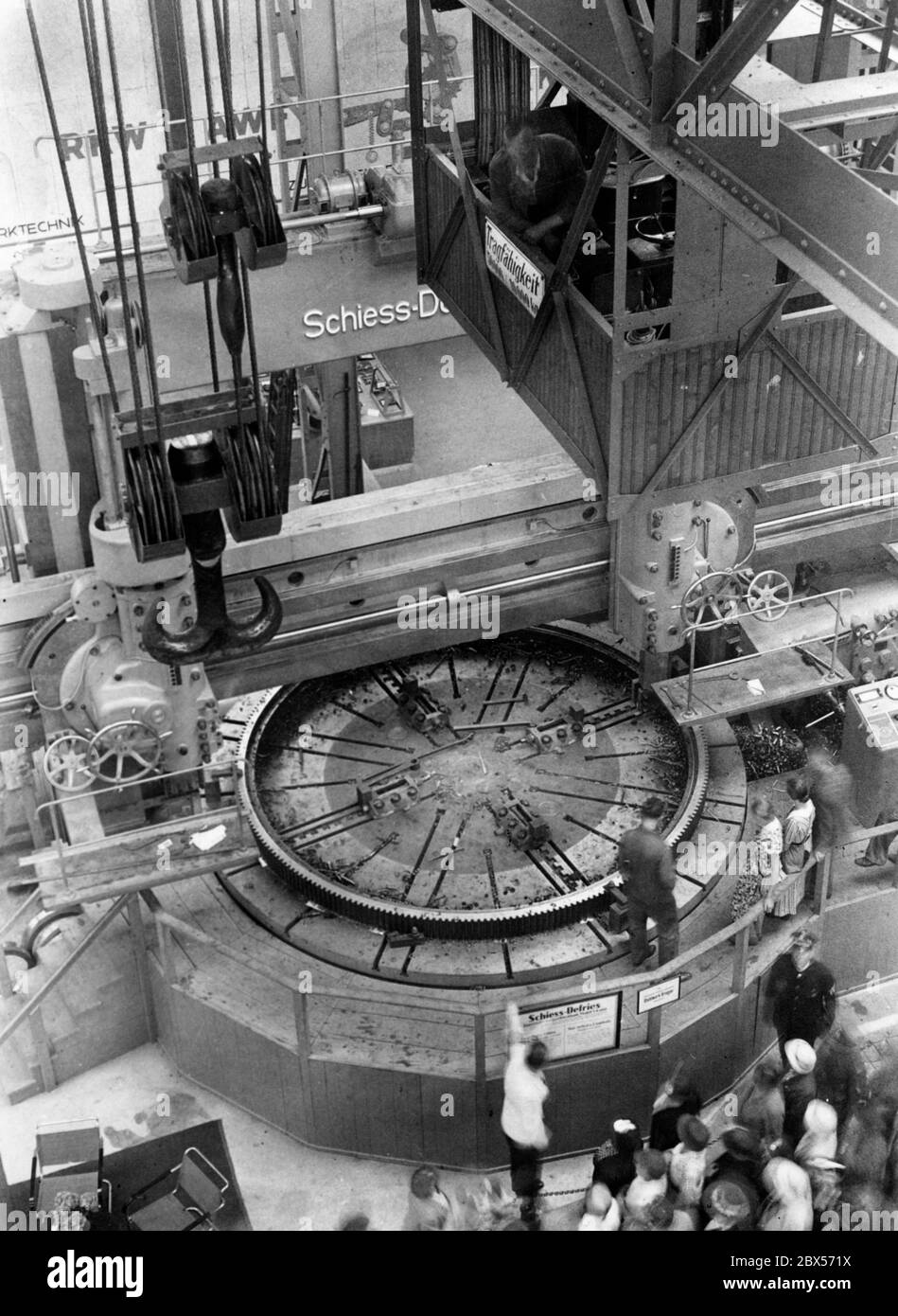 Ansicht einer Doppelsäulendrehmaschine der Firma Schiess-Defries AG mit einem Durchmesser von sechs Metern in der Halle 'Werkzeugmaschinen' der Reichausstellung 'Saffendes Volk' in Düsseldorf. Auf der Platte befindet sich eine große Zahnkranz für die Bearbeitung. Stockfoto