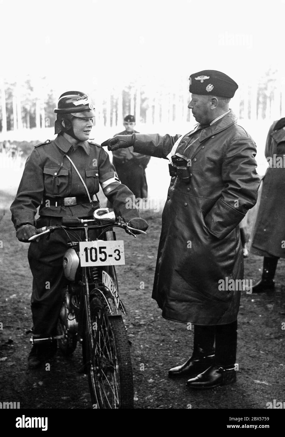 NSKK Corps-Führer Adolf Huehnlein spricht auf der 7. Reichssitzung der Motor HJ in Bad Gandersheim mit einem Teilnehmer der Offroad-Probefahrt. Der junge Mann sitzt auf einem Motorrad vom Typ NSU-D-Quick. Stockfoto