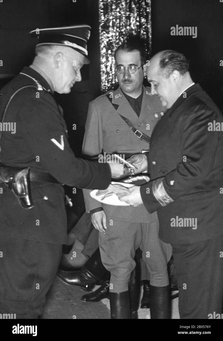 Der spanische Staatssekretär Nicolas Franco, Bruder von Francisco Franco und Ramon Franco, gibt einem SS-Hauptsturmführer vor Beginn der Schlusskundgebung des Reichsparteitages der Arbeit in Nürnberg ein Autogramm. Stockfoto