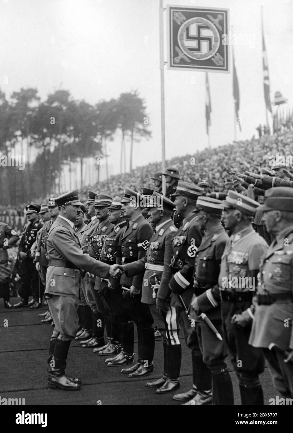 Bei den Feierlichkeiten zur Eröffnung der Nazi-Kampfspiele und der Grundsteinlegung für das Deutsche Stadion auf dem Reichsparteigelände begrüßt Adolf Hitler die Ehrengäste mit einem Händedruck, darunter auch Reichsarbeitsführer Konstantin Hierl, Reichssportleiter Hans von Tschammer und Osten, Generalleutnant Friedrich Christiansen, Reichskinder Baldur von Schirach, Korpsführer Adolf Huehnlein, Reichssouverneur Franz Ritter von Epp, Reichskapiteur Franz Xaver Schwarz. Stockfoto