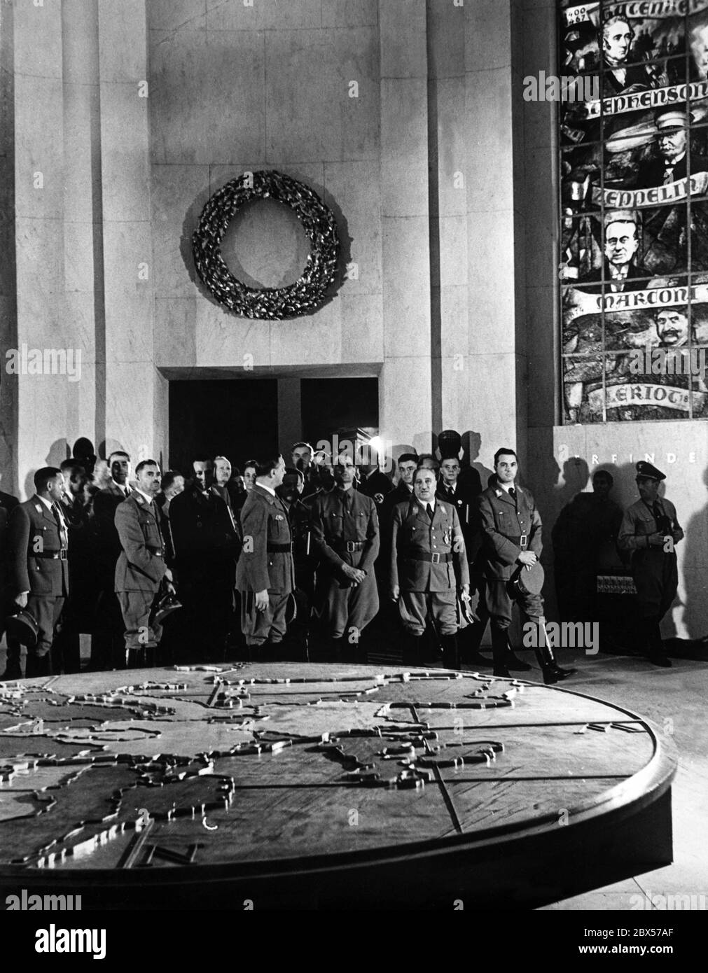 Robert Ley, Rudolf Hess und Alfred Rosenberg (in der ersten Reihe von rechts nach links) als Gäste im Ehrensaal der Ausstellung "Europas Schicksalskampf im Osten", die in der Nürnberger Norishalle stattfand. An der Wand sind Porträts (von oben) von Johannes Gutenberg, Graf Ferdinand von Zeppelin, Guglielmo Marconi, Louis Bleriot. Hinter links ist Albert Speer. Stockfoto