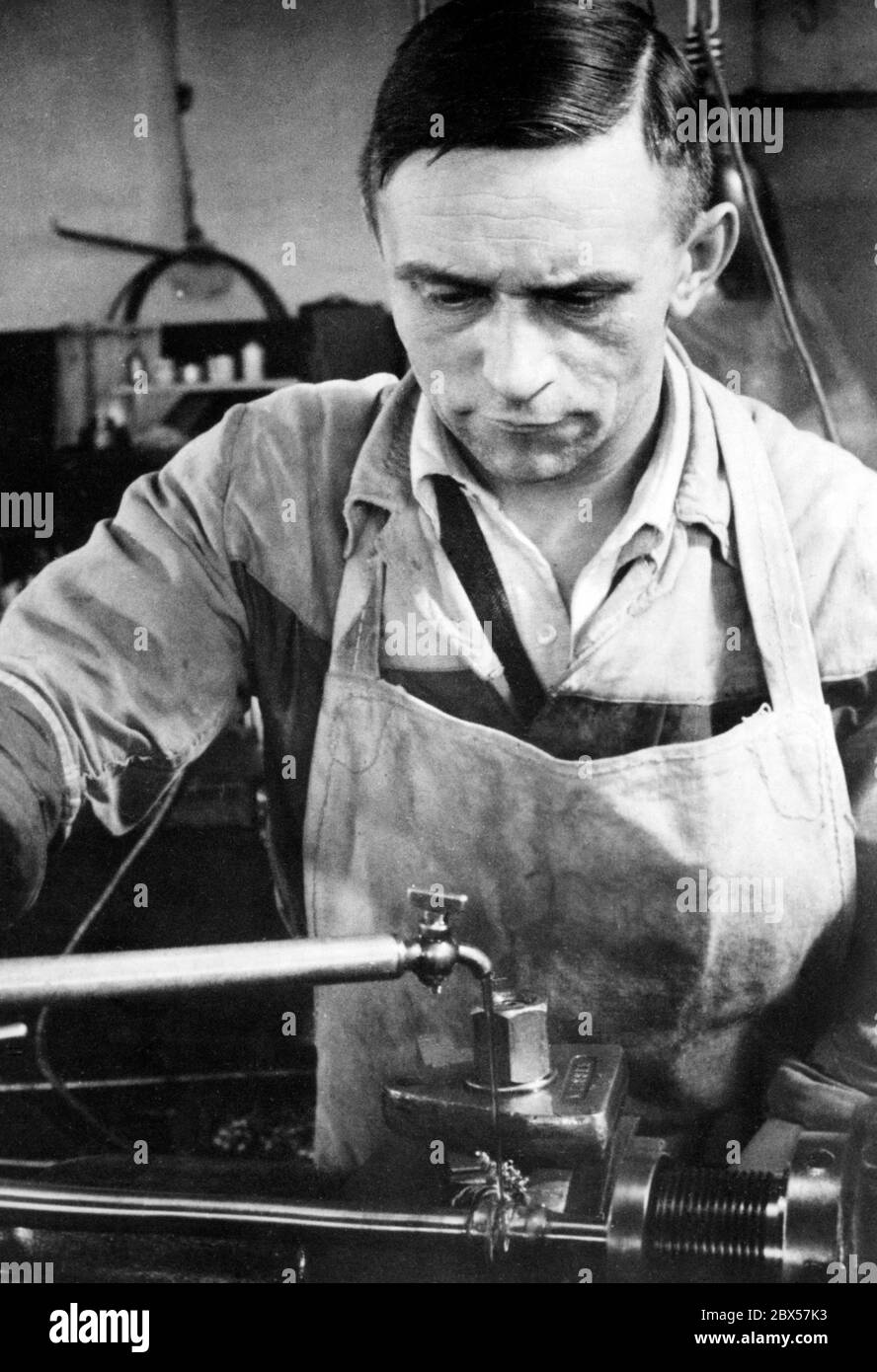 Ein Mitarbeiter einer Rüstungsfabrik kühlt sein Werkstück beim Wenden mit Wasser, damit es nicht zu viel aufheizt. Stockfoto