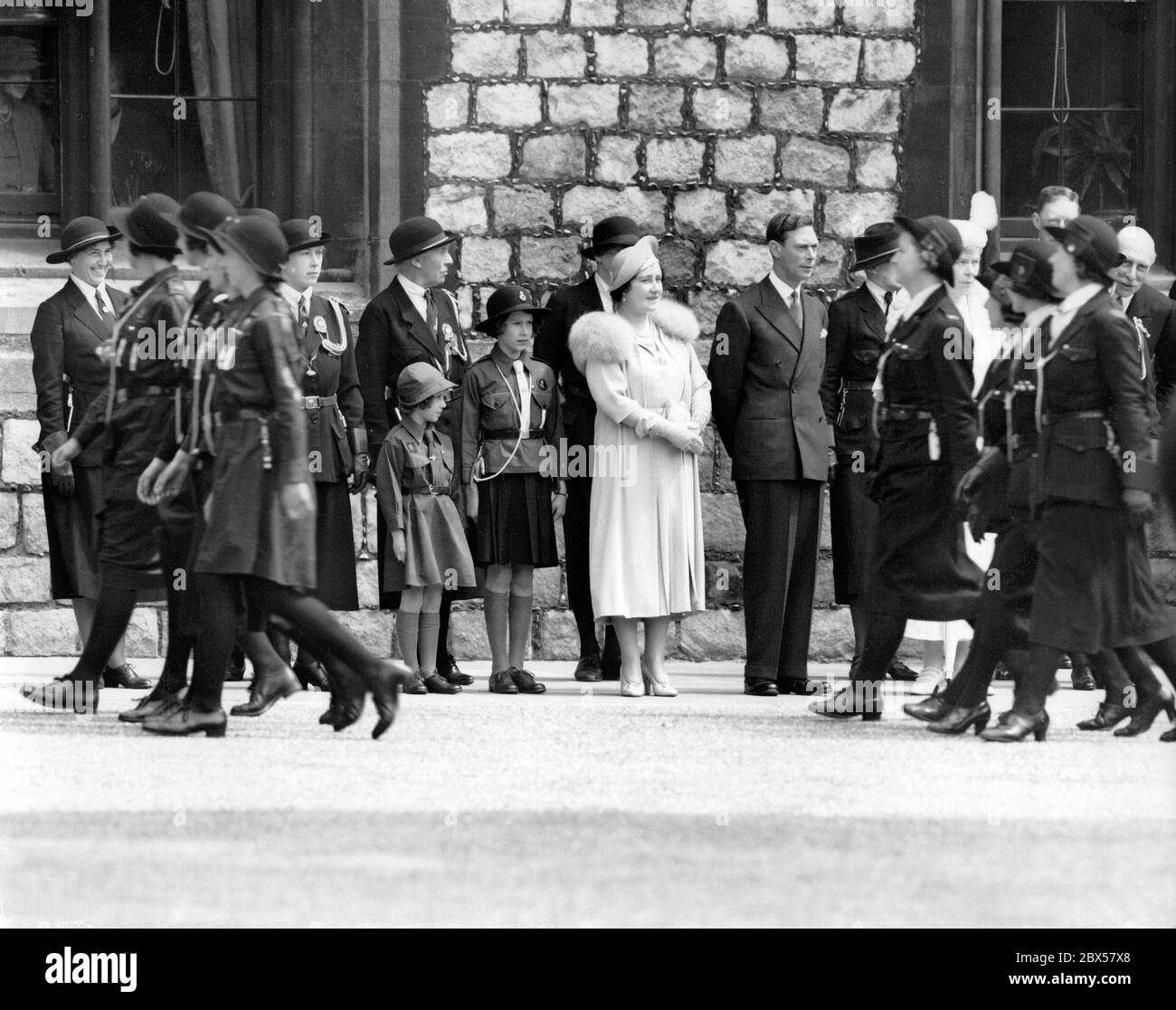 Von links nach rechts: Prinzessin Margaret Rose (in Uniform als Brownie), Prinzessin Elizabeth (in Uniform als Guide), Königin Elizabeth, König Georg VI und Königin Mutter Maria (leicht bedeckt) bei einer Parade von Pfadfindern. Stockfoto