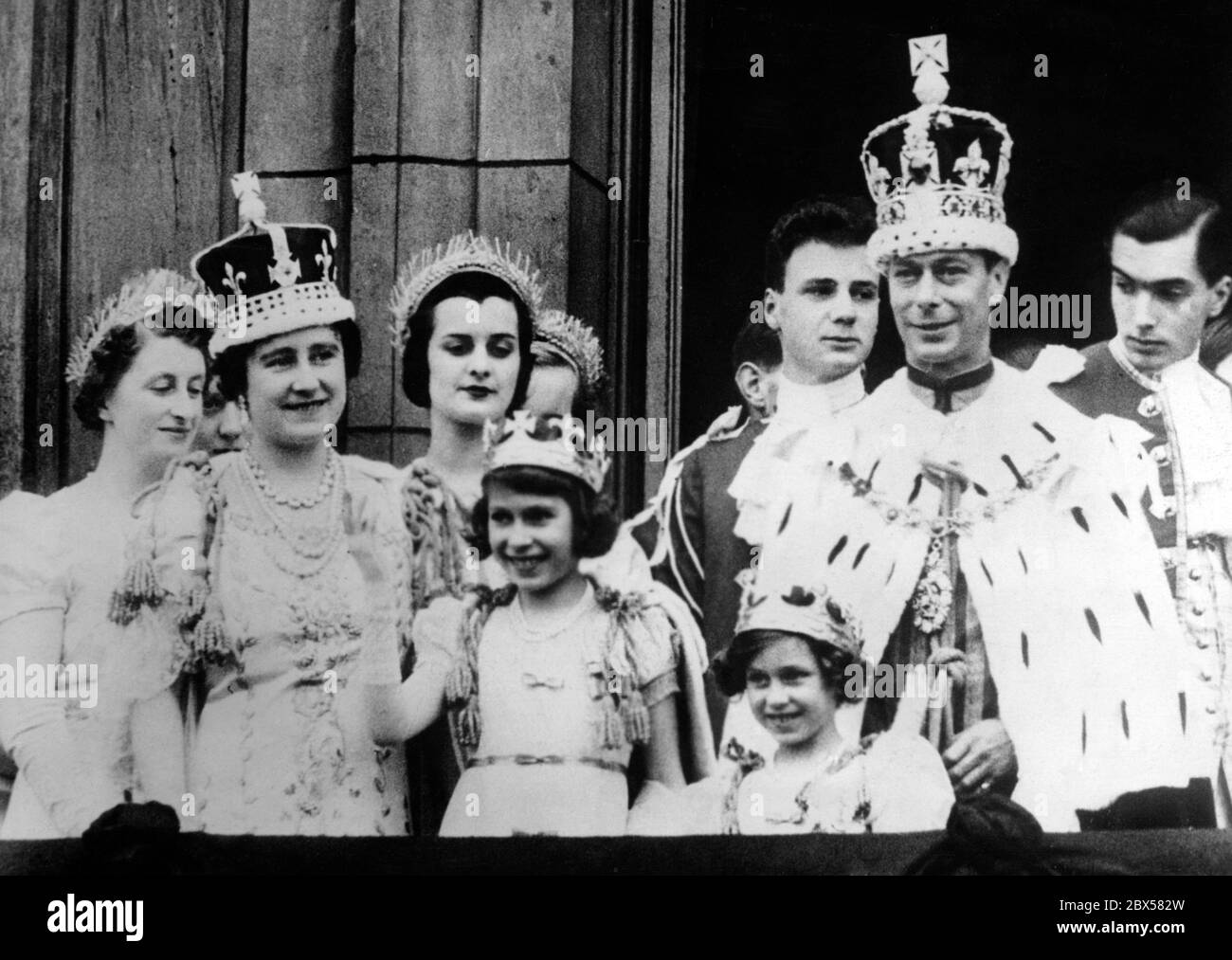 Nach der Krönung stehen Königin Elizabeth, Prinzessin Elizabeth, Prinzessin Margaret Rose und König George VI. Mit dem Rest der königlichen Familie auf dem Balkon des Buckingham Palace und winken der Menge zu. Stockfoto