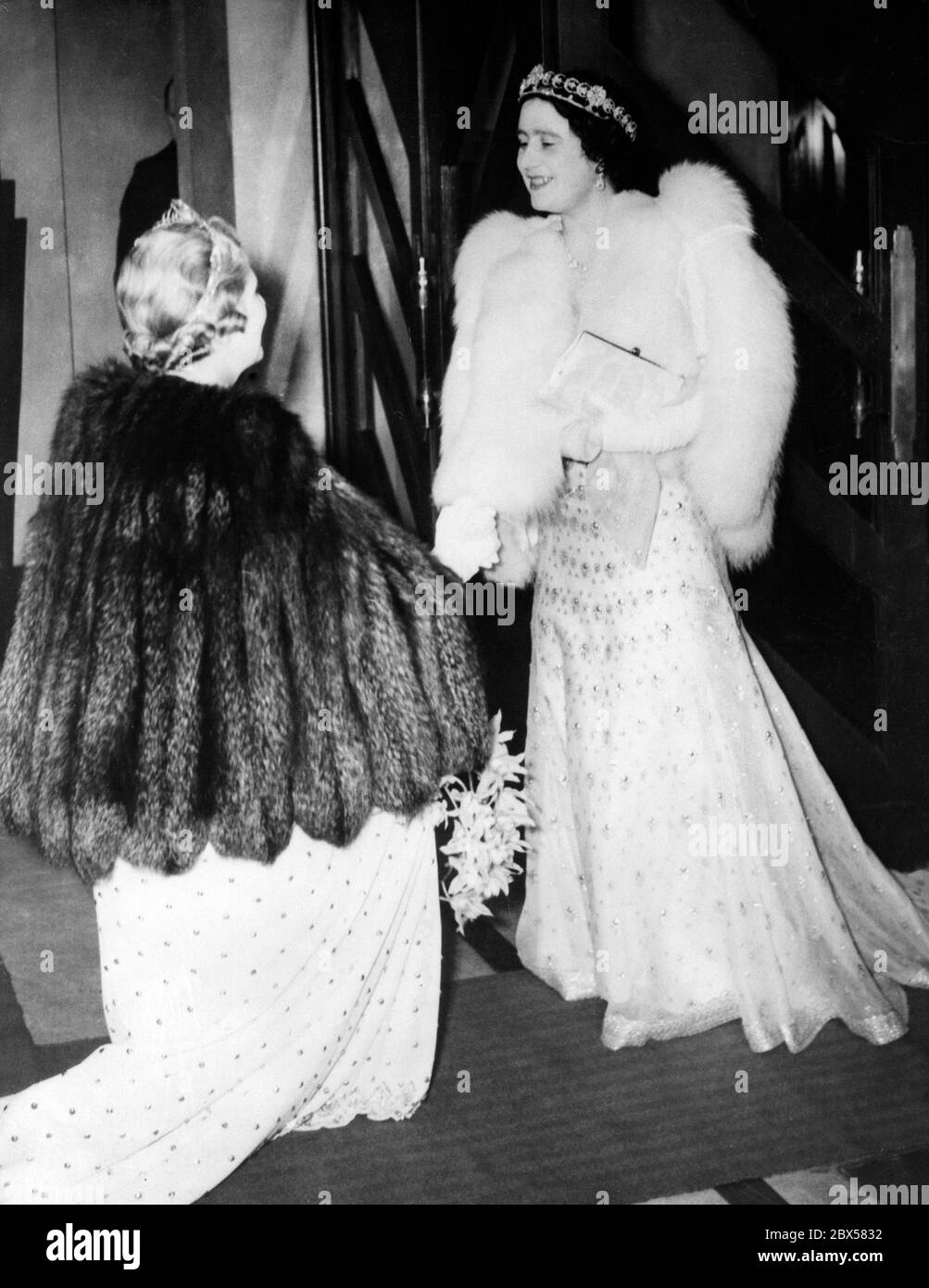 Königin Elizabeth wird bei einer Aufführung des französischen Nationaltheaters 'Comedie Francaise' im Savoy Hotel in London von Lady Bessborough, der Frau des Earl of Bessborough, der Vorsitzenden der Anglo-French Art and Travel Society, mit einem Blumenstrauß überreicht. Stockfoto