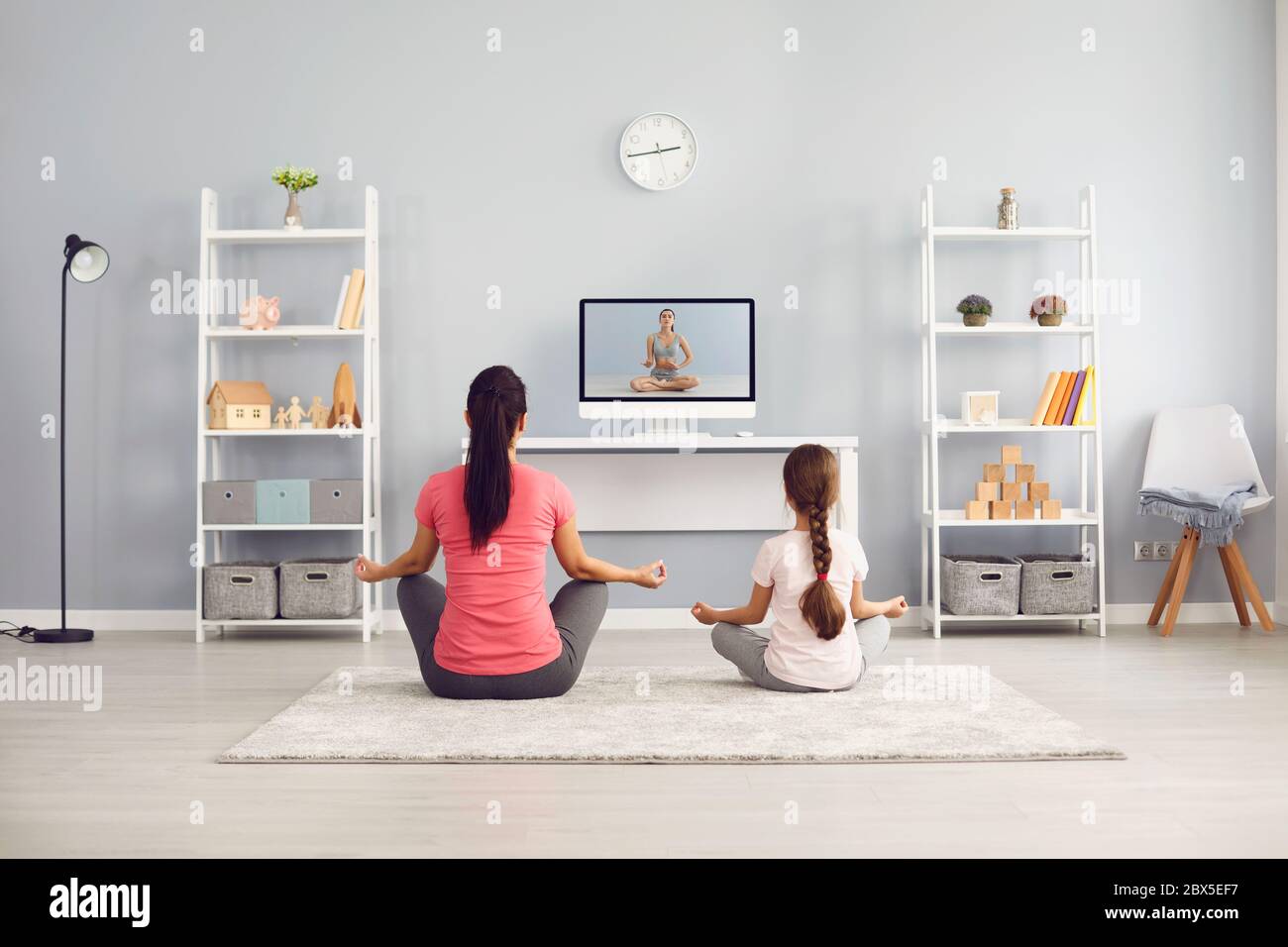 Yoga Praxis Familie. Mutter und Mädchen üben Yoga Meditation Online-Training Videotrainer sitzt auf dem Boden im Raum. Stockfoto