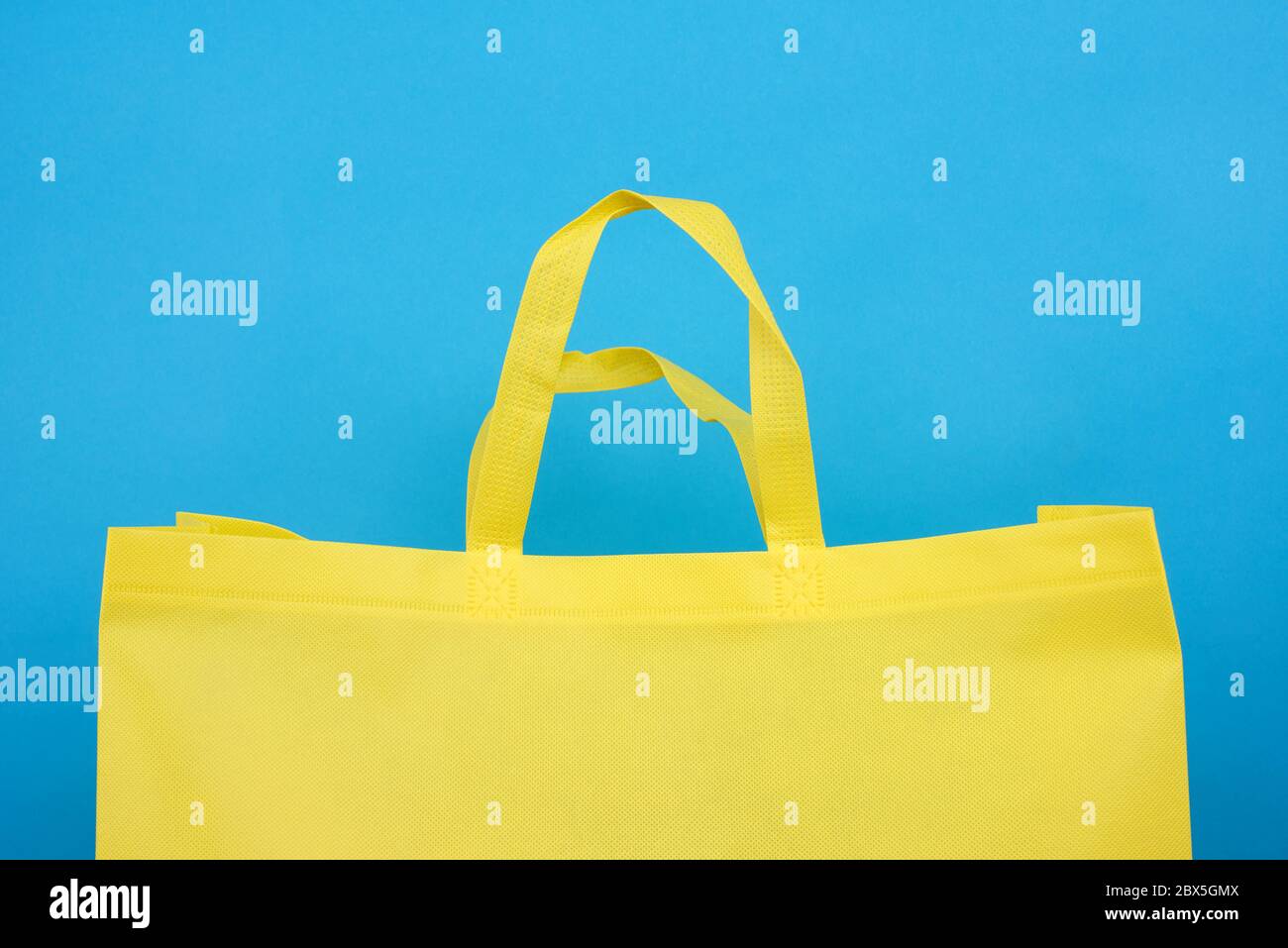 Wiederverwendbare gelbe Viskose Tasche auf blauem Hintergrund, Kunststoff Abfallvermeidung Konzept Stockfoto