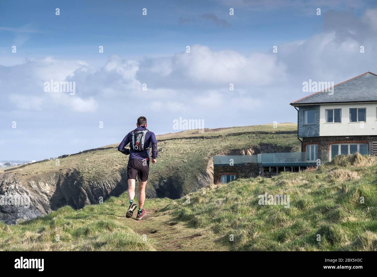 Ein Mann, der auf einem Fußweg am Pentire Point East an der Küste von Newquay in Cornwall läuft. Stockfoto