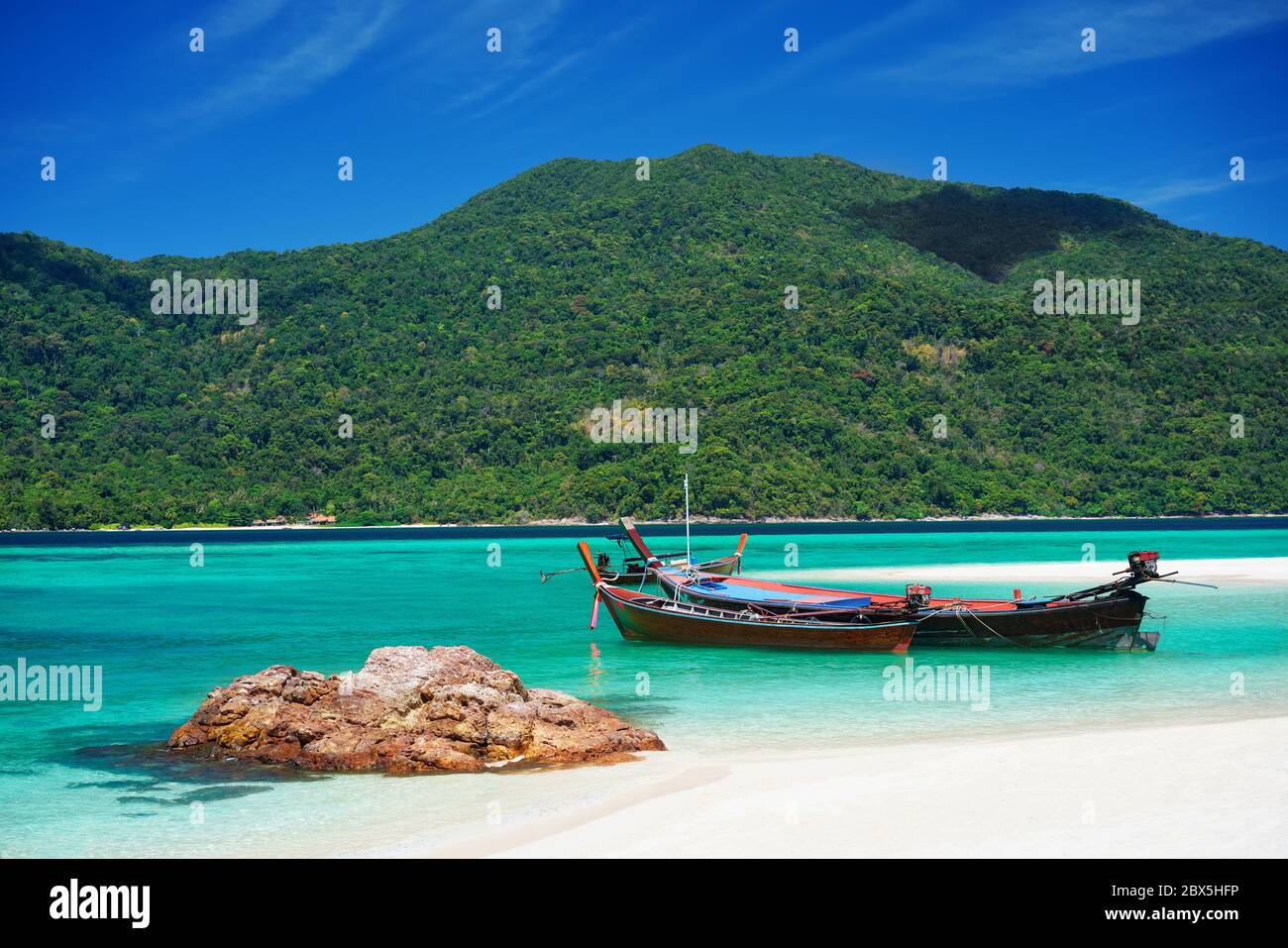 Boot an der tropischen Küste mit weißem Sandstrand und türkisfarbenem Wasser. Sommer Urlaub Hintergrund Stockfoto