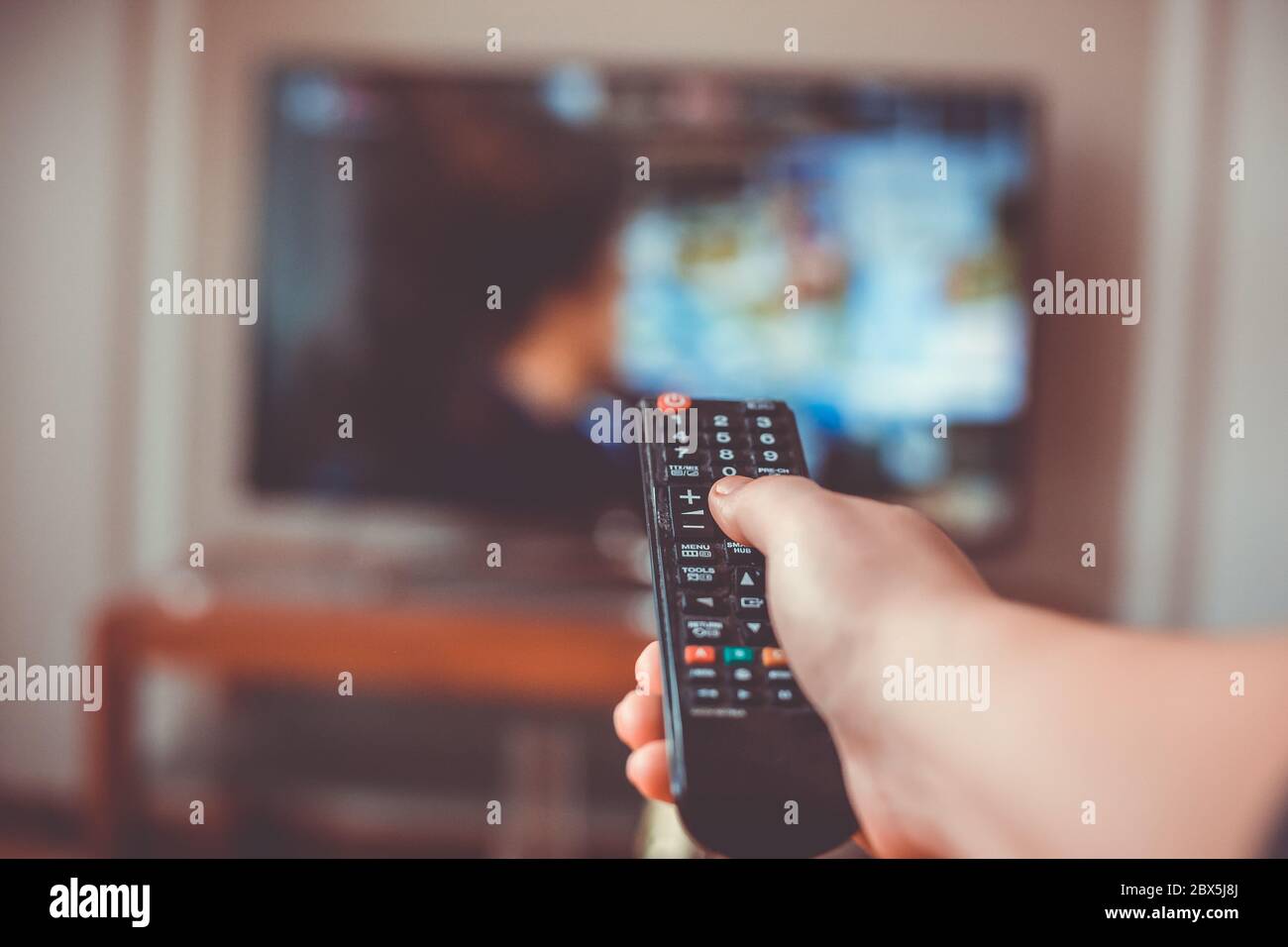 Nahaufnahme der Hand mit der Fernbedienung Fernseher und drückt die Taste, Technologie-Konzept Stockfoto
